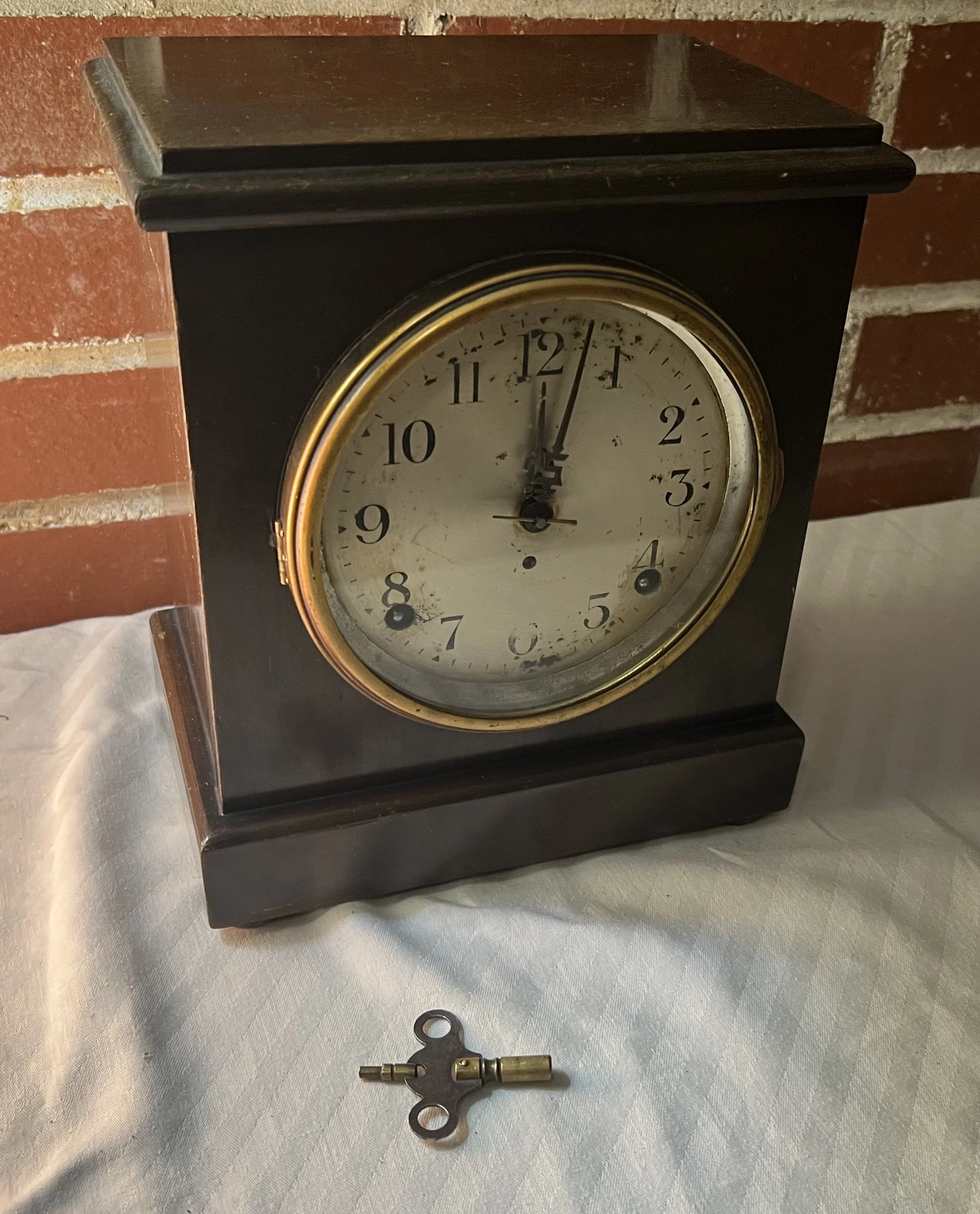 Antique Seth Thomas mantel clock with a dark, adamantine veneer finish and its original winding key. 
Brand: Seth Thomas, known for high-quality American timepieces. 
Material: Adamantine finish, a patented celluloid veneer applied to wooden cases, o