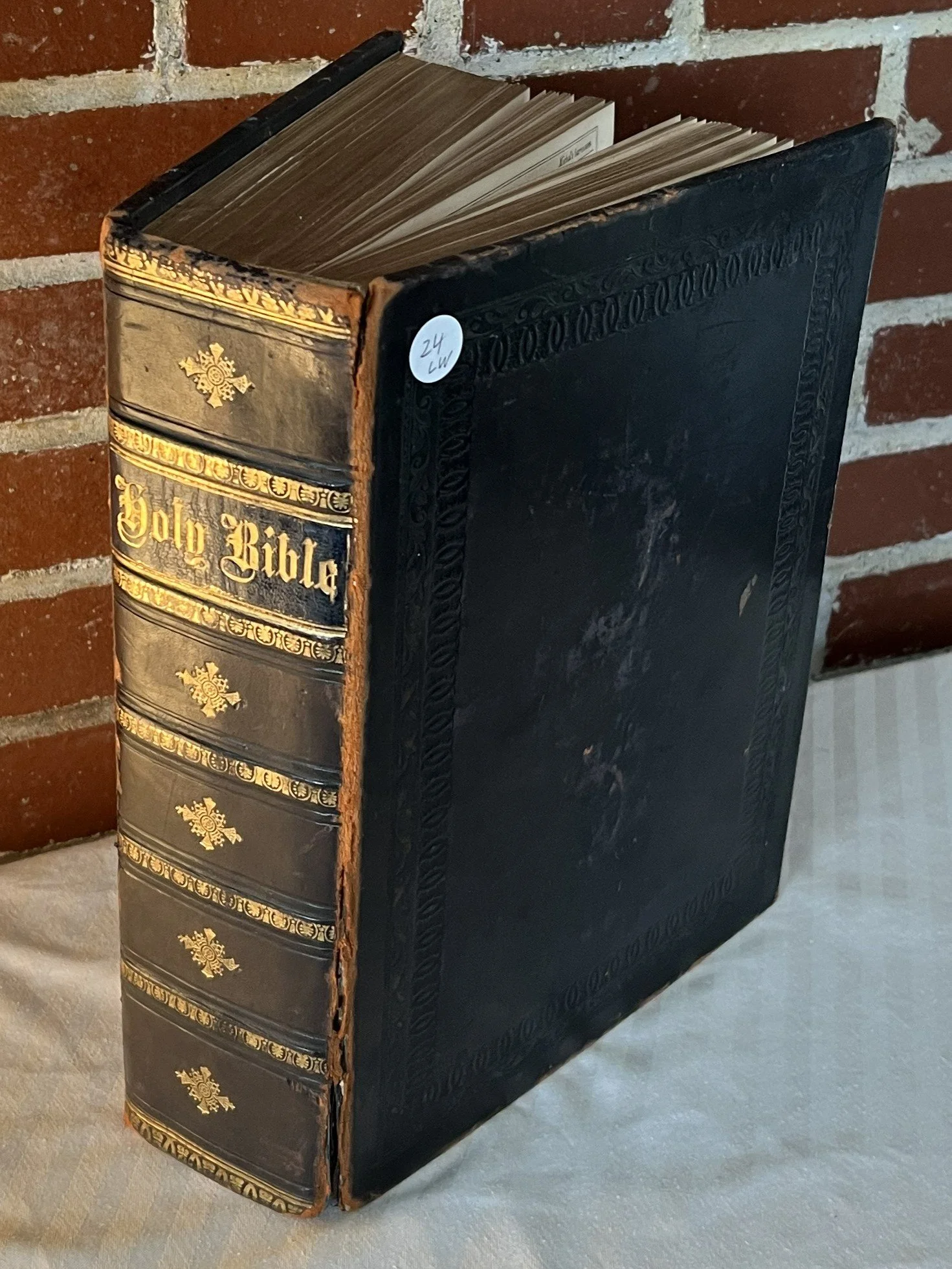 Old black leather-bound Holy Bible with gold lettering and decorative gold embellishments on the spine