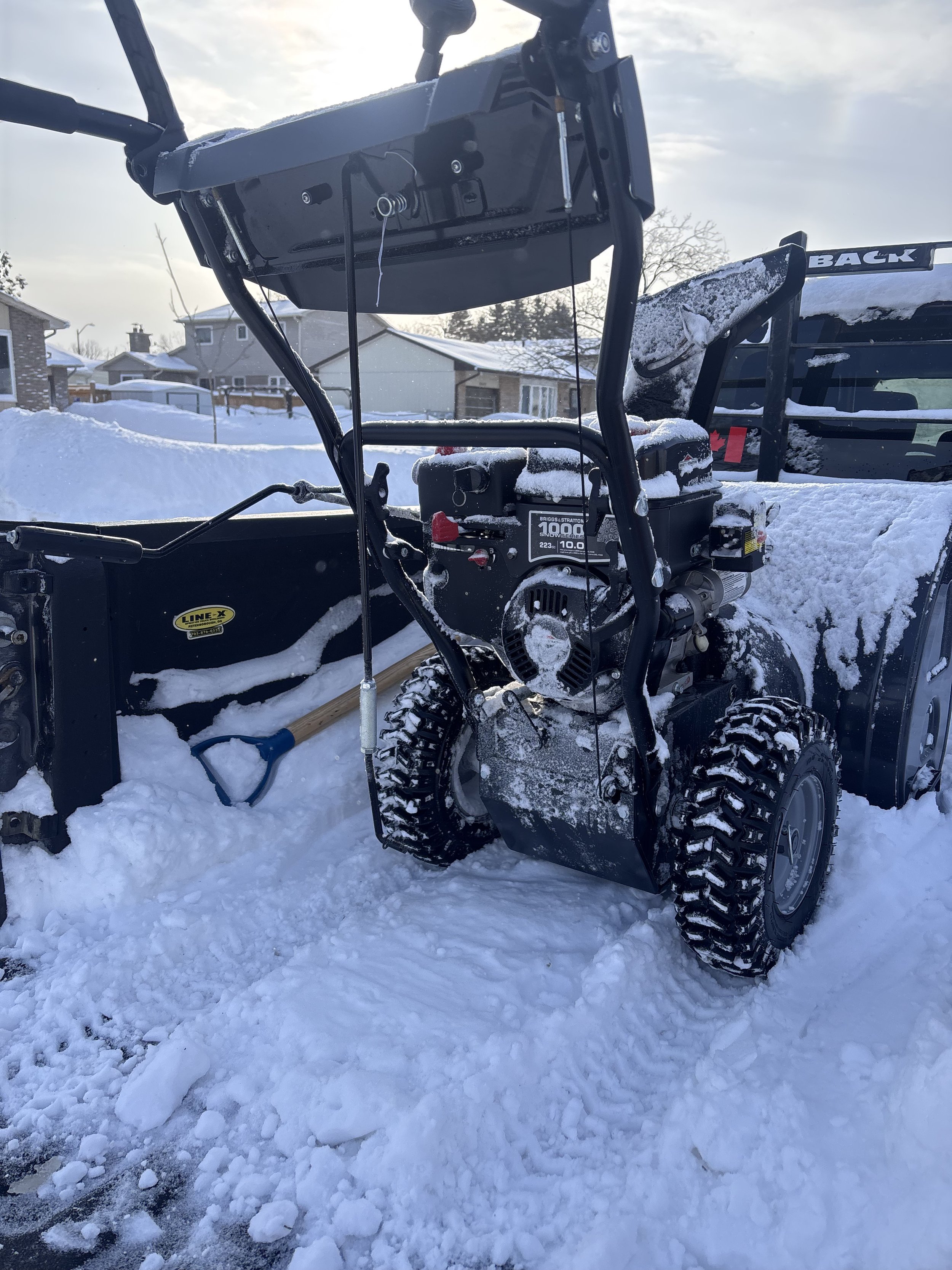 Two workers in winter gear clearing snow from a roadway with shovels.