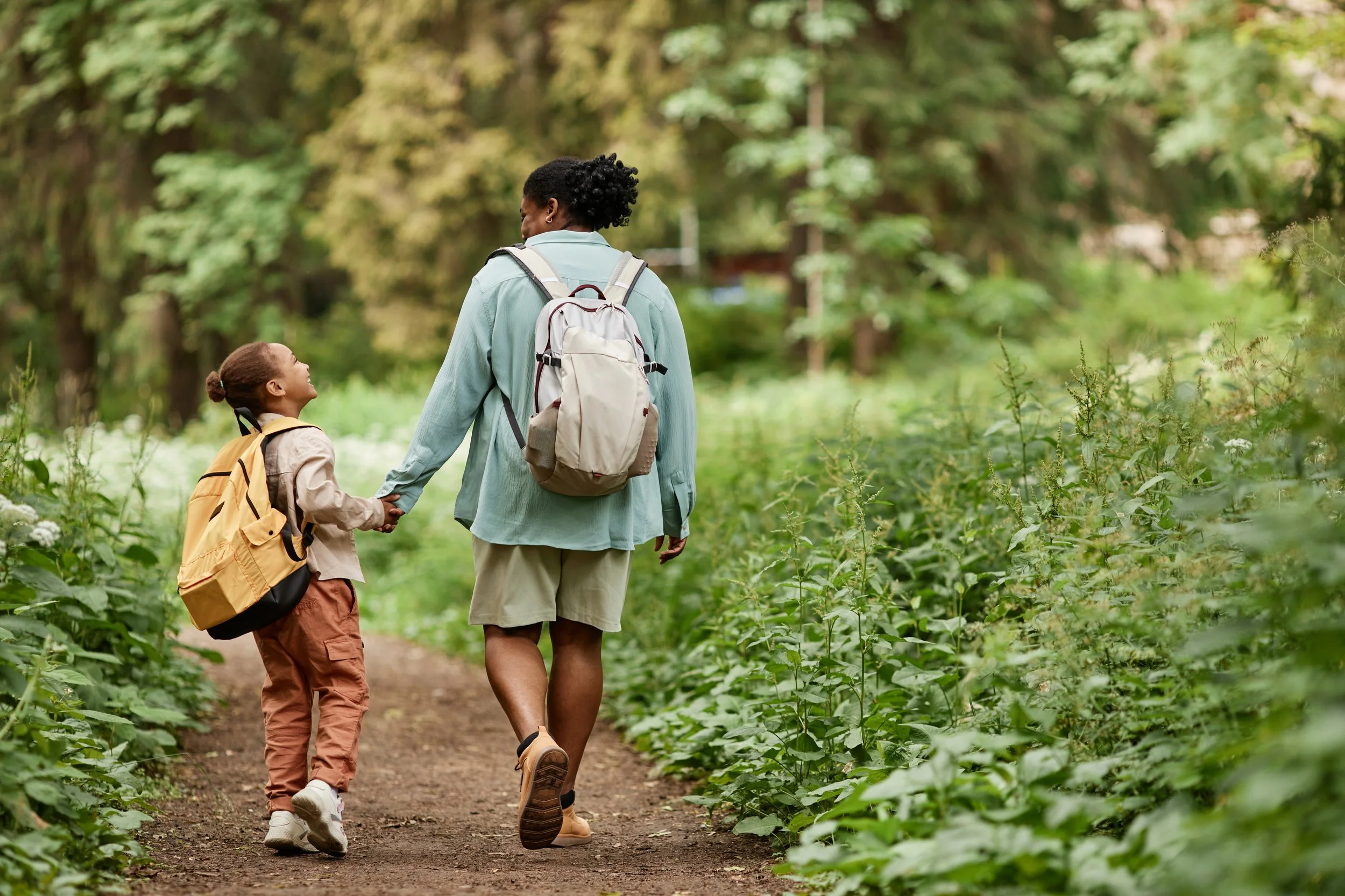 Adult and child walking together on a wooded trail