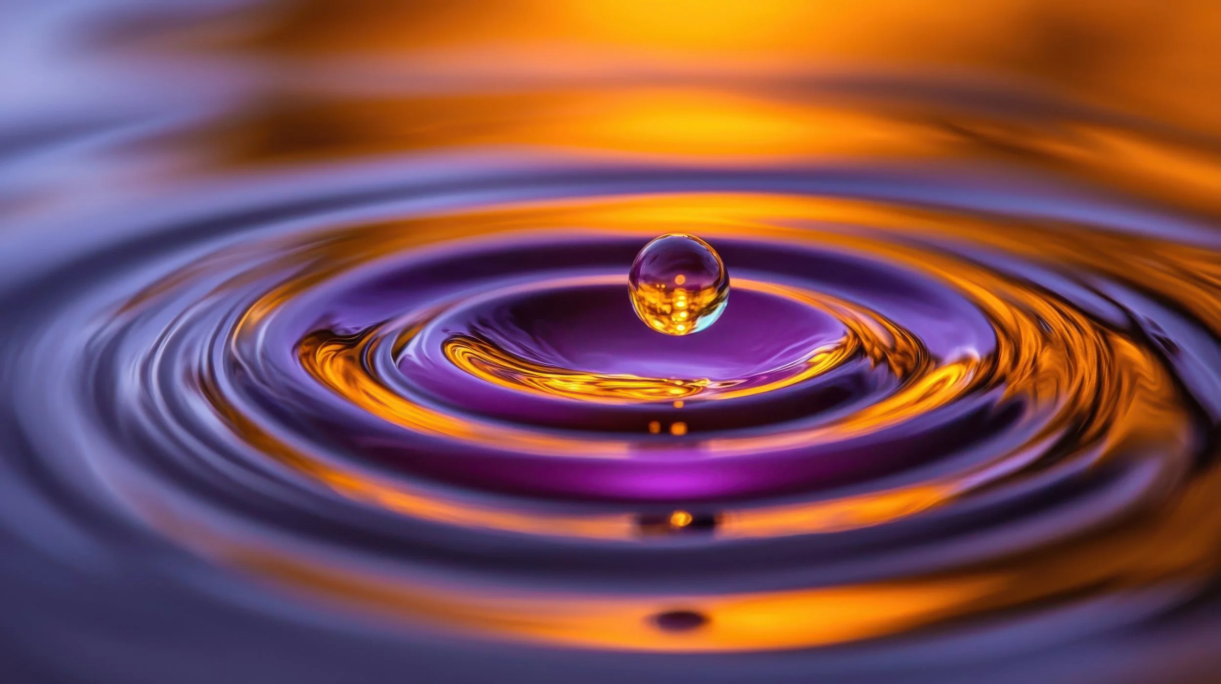 Water droplet creating concentric ripples on the surface of calm water
