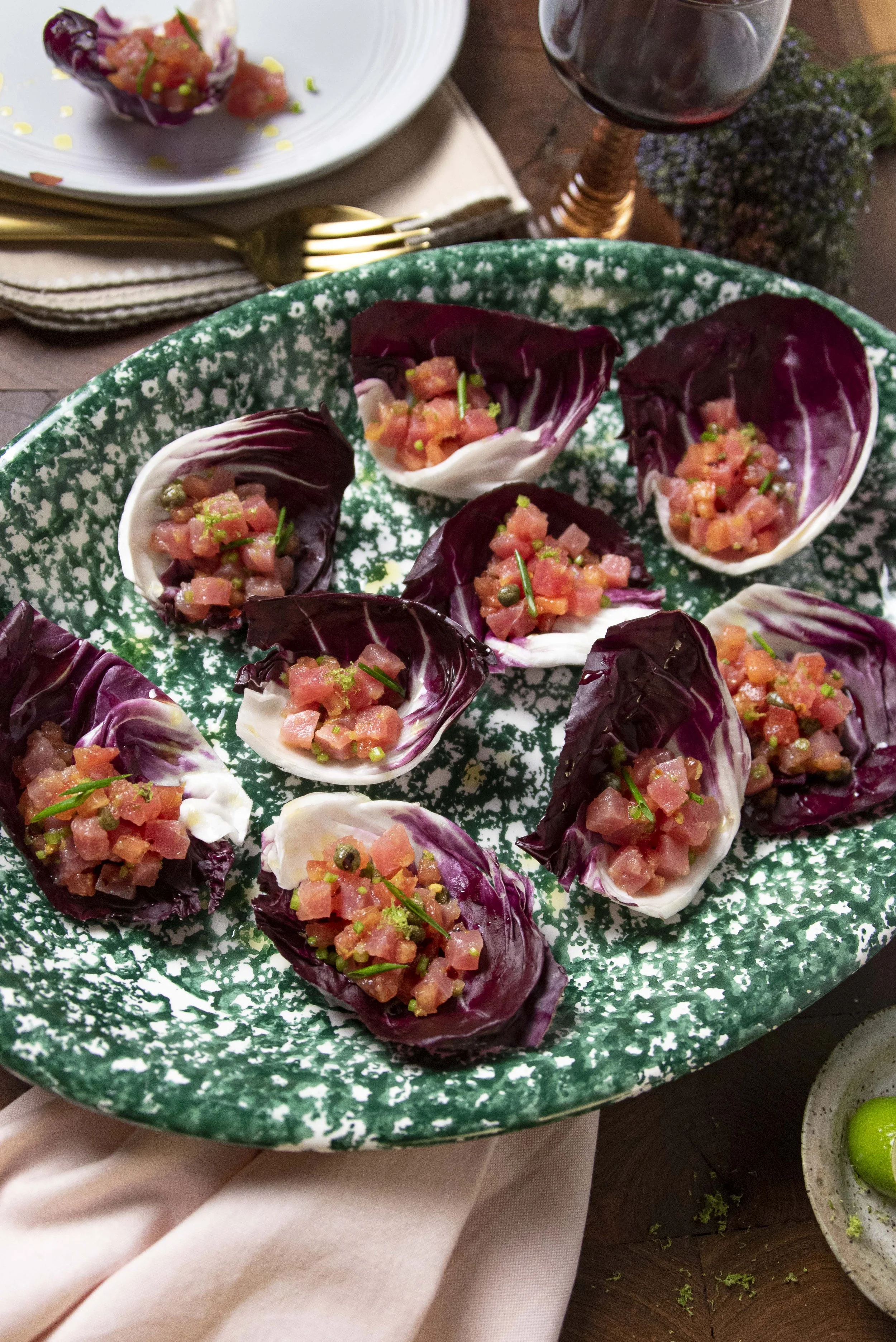 Bowl of endive leaves topped with salmon tartare and garnished with herbs.