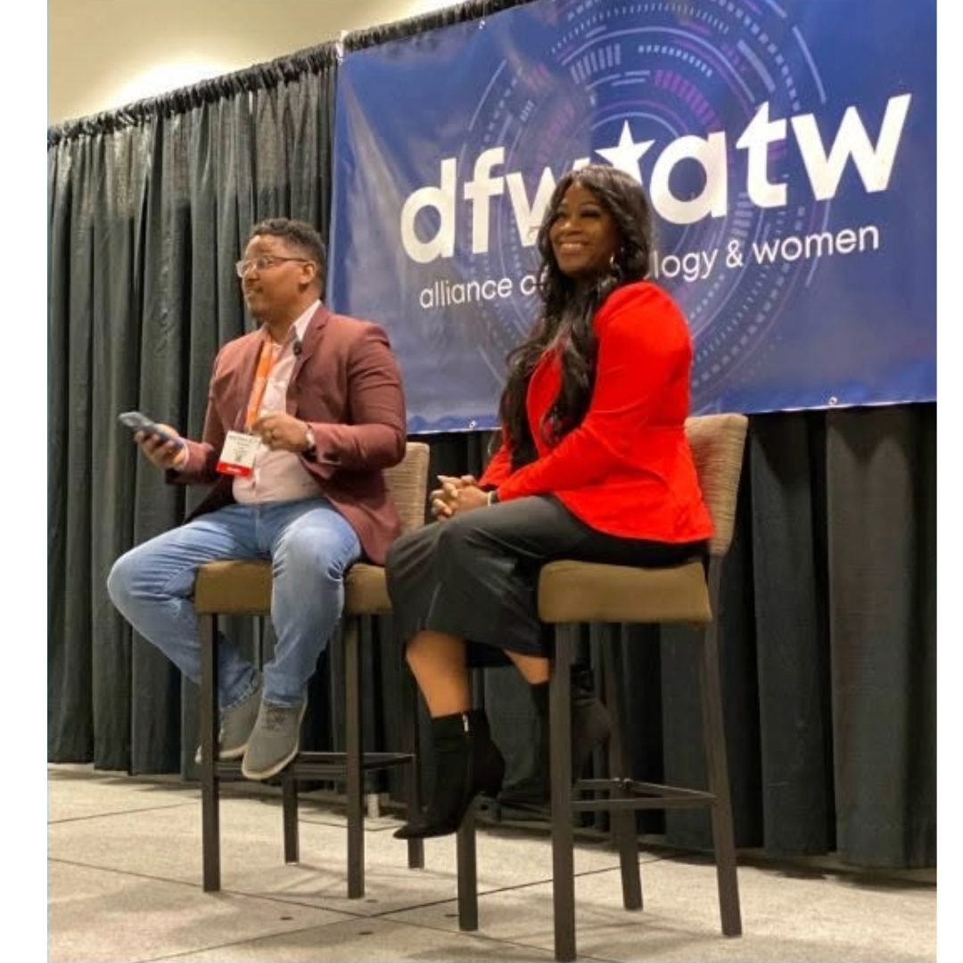 Two people sitting on high chairs on a stage at a conference, with a blue banner behind them that reads 'dfw atw alliance technology & women'.