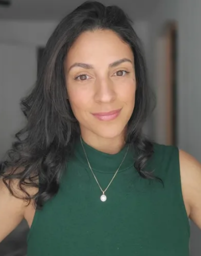 Yasmin Romero, A woman with dark, wavy hair wearing a green sleeveless top and a silver necklace smiling at the camera.