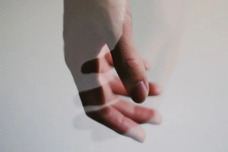 A person holding an orange between their fingers.