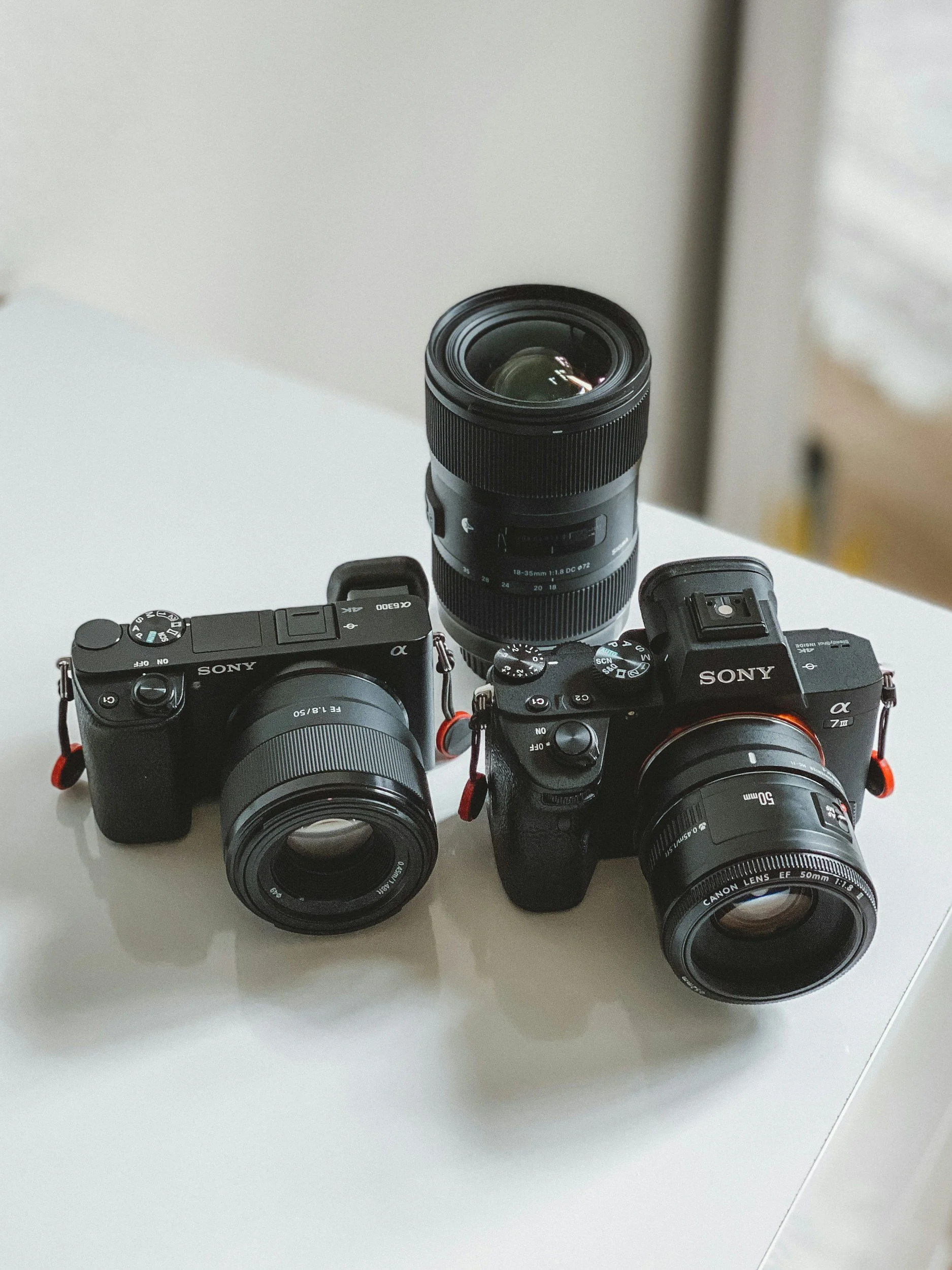 Three digital cameras with attached lenses on a white surface.