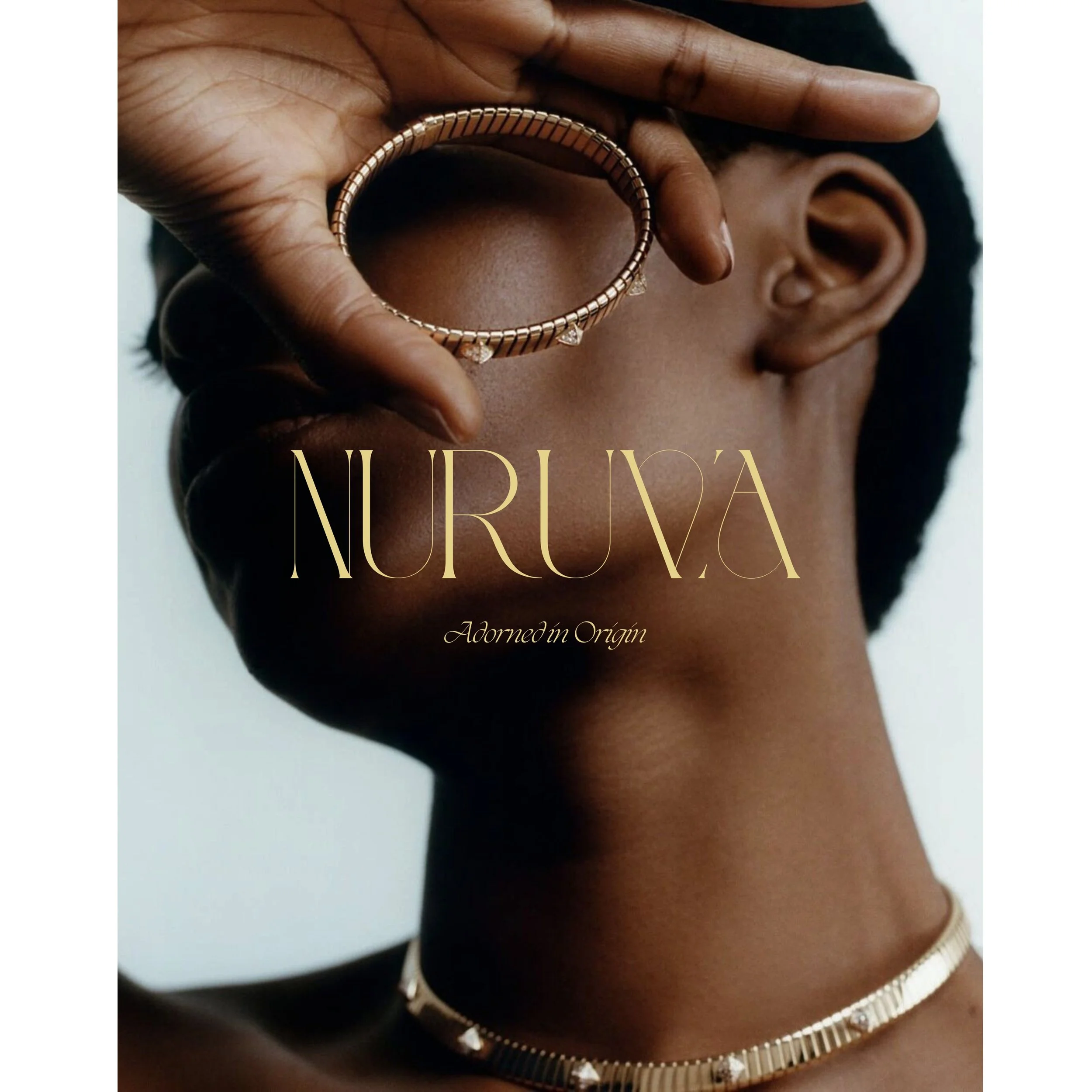 Close-up of a person wearing a gold bracelet and a gold chain, with their hand near their face, highlighting jewelry on their wrist and neck.