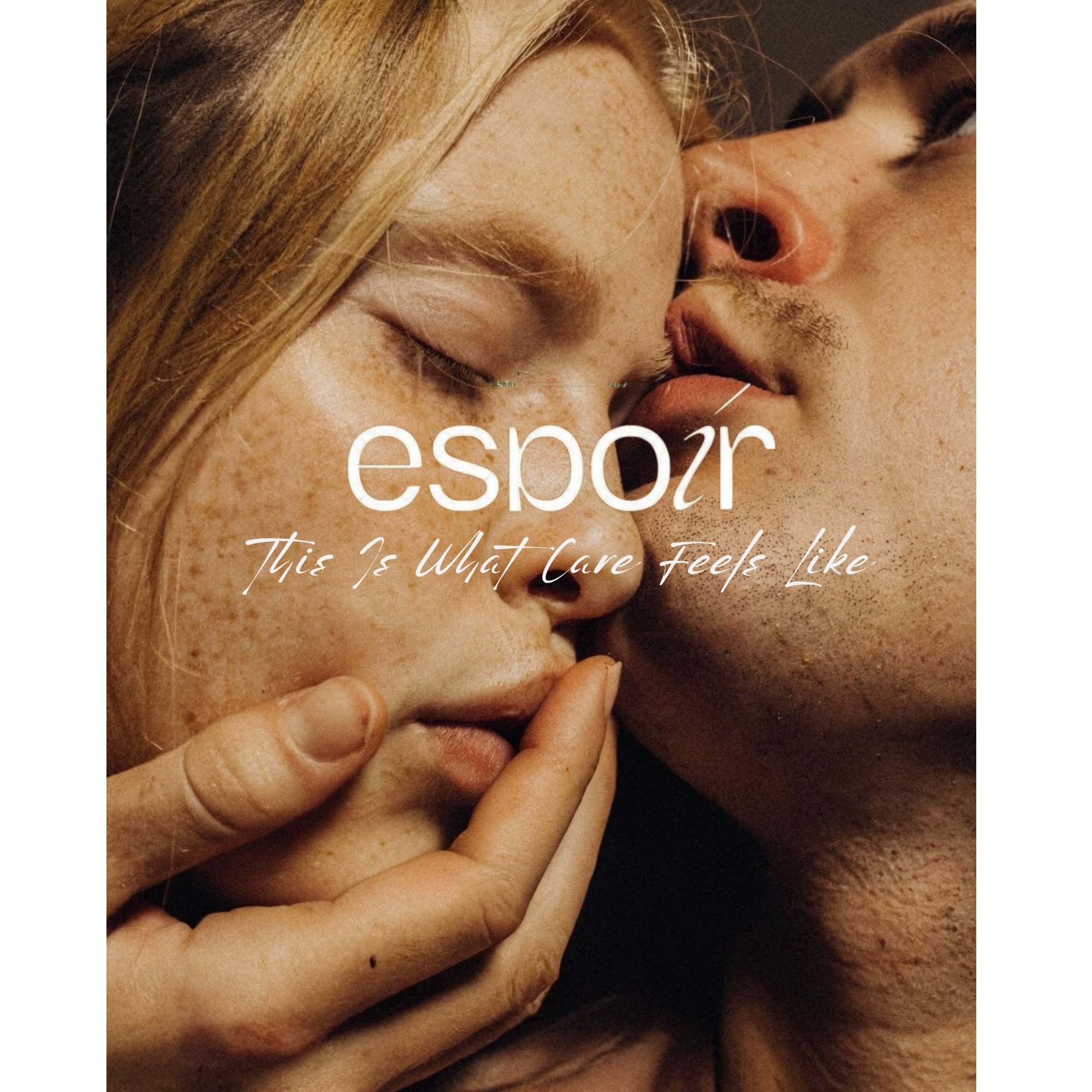 Close-up of a young woman with red hair and freckles, and a young man with darker skin tone, lips close to each other in an intimate pose, with the woman holding a finger to her lips. Text overlays read 'esp0r' and 'This Is What Care Feels Like'.