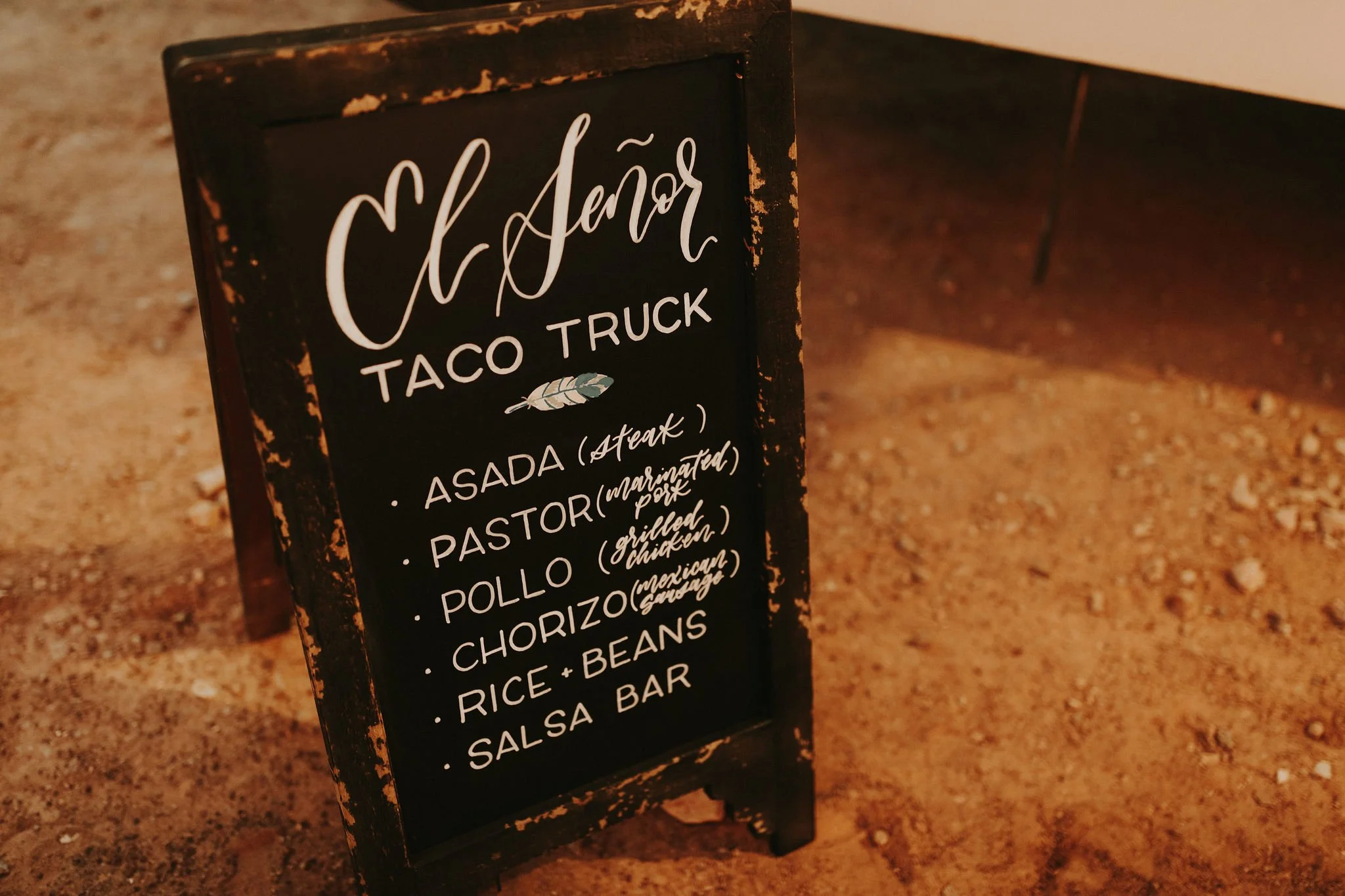 A black chalkboard sign with a distressed frame advertising