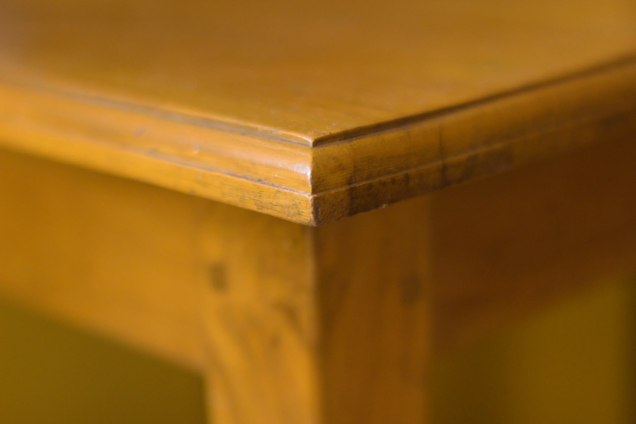 Close-up photo of the corner of a wooden table showing its polished surface and edges.