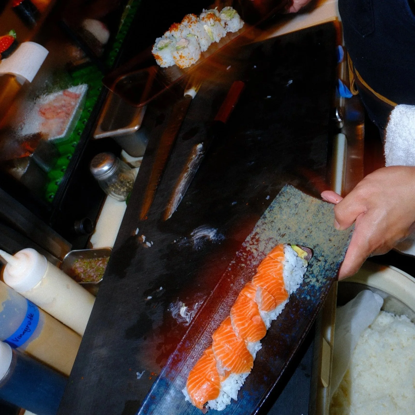 Assorted sushi rolls and salmon nigiri on a black serving plate at a restaurant