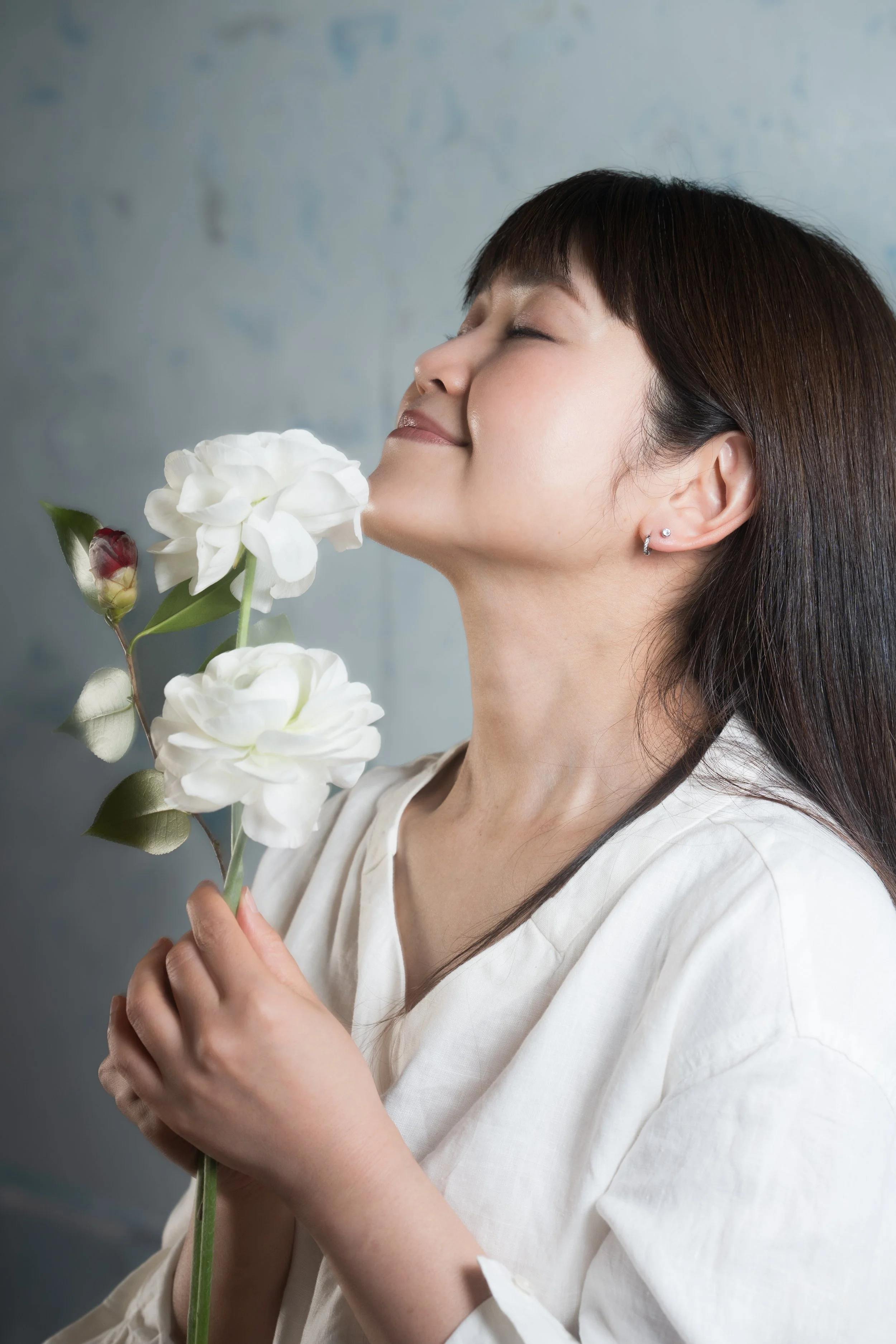 白い花を持ち、顔を近づけてにおいを嗅ぐ笑顔の女性