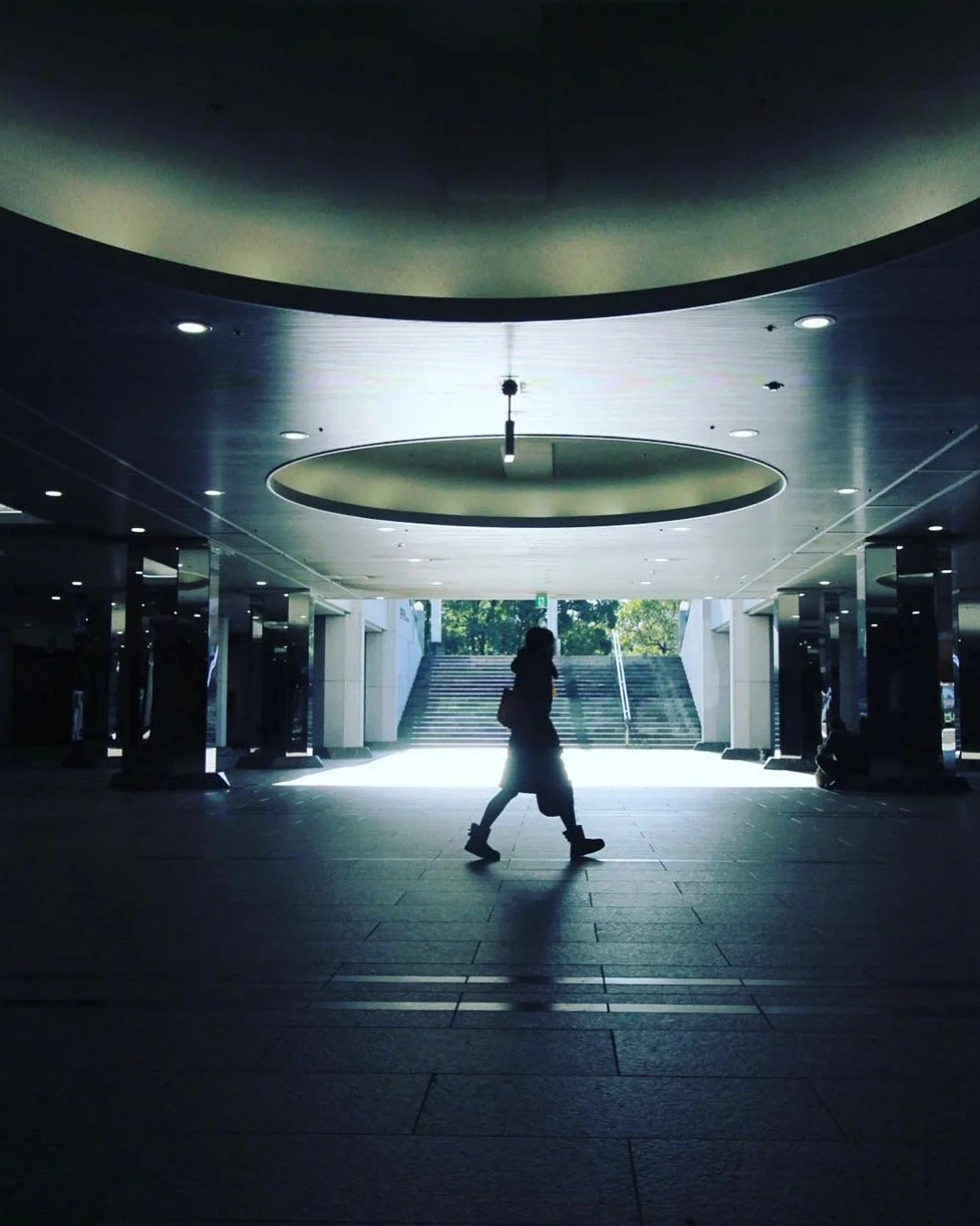 建物の内部で、人が歩いている silhouetted silhouette with stairs and bright exit in the background.