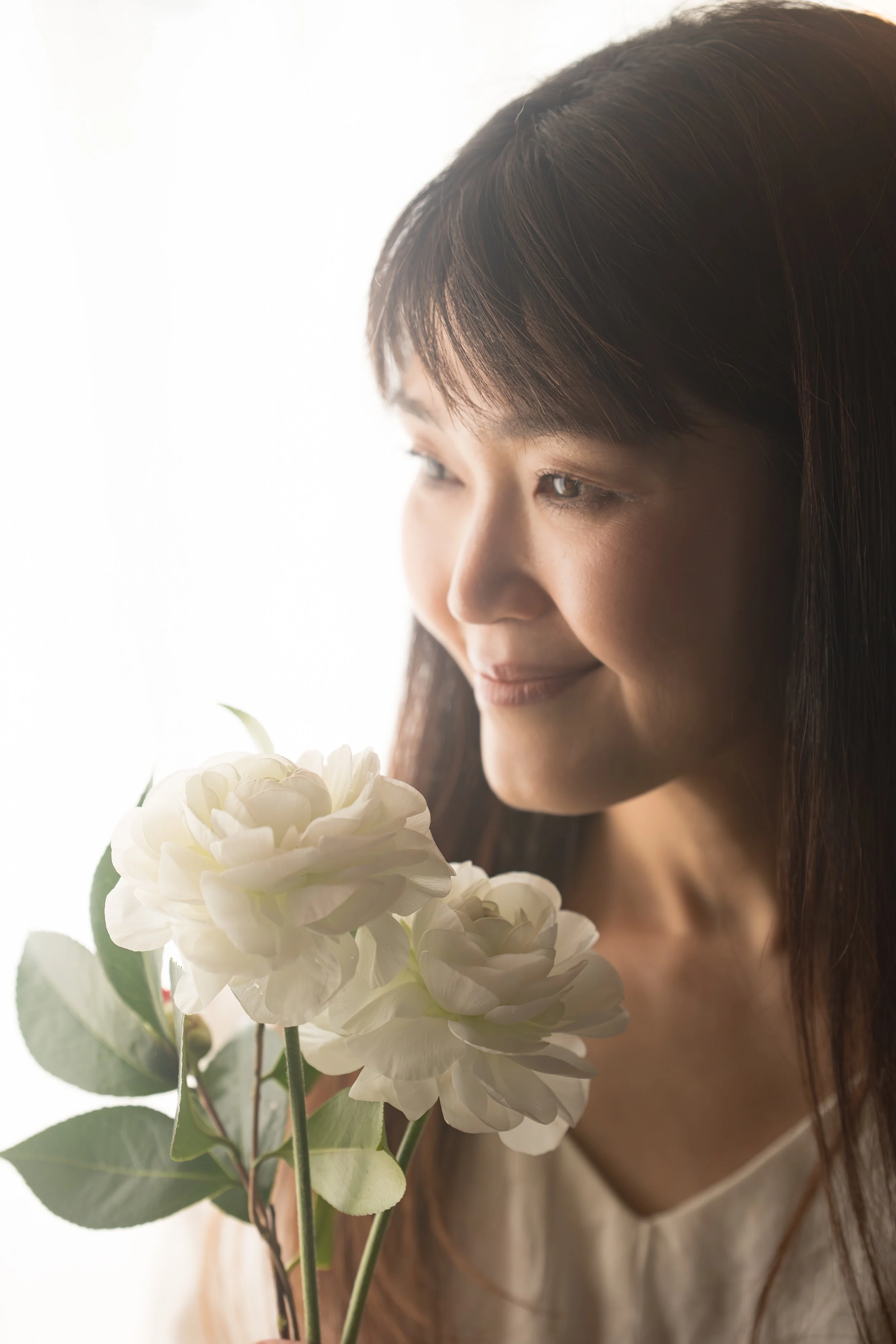 白い花を持つ女性の横顔の写真