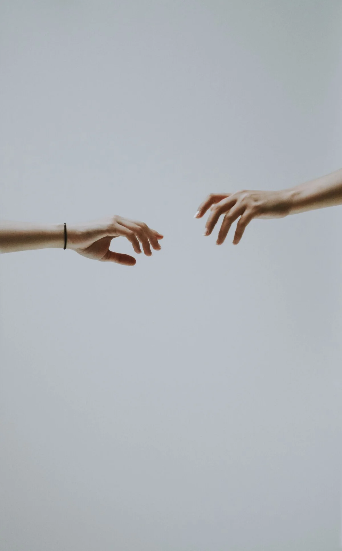 Two hands reaching out towards each other against a plain white background, reminiscent of Michelangelo's "The Creation of Adam."