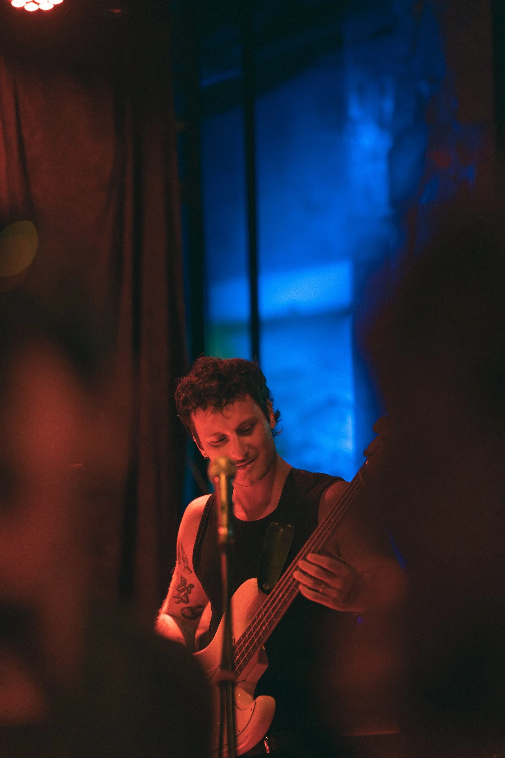 Live music performance in Noosa with guitarist under red and blue stage lighting, blurred foreground and intimate venue atmosphere, Sunshine Coast event and nightlife photography