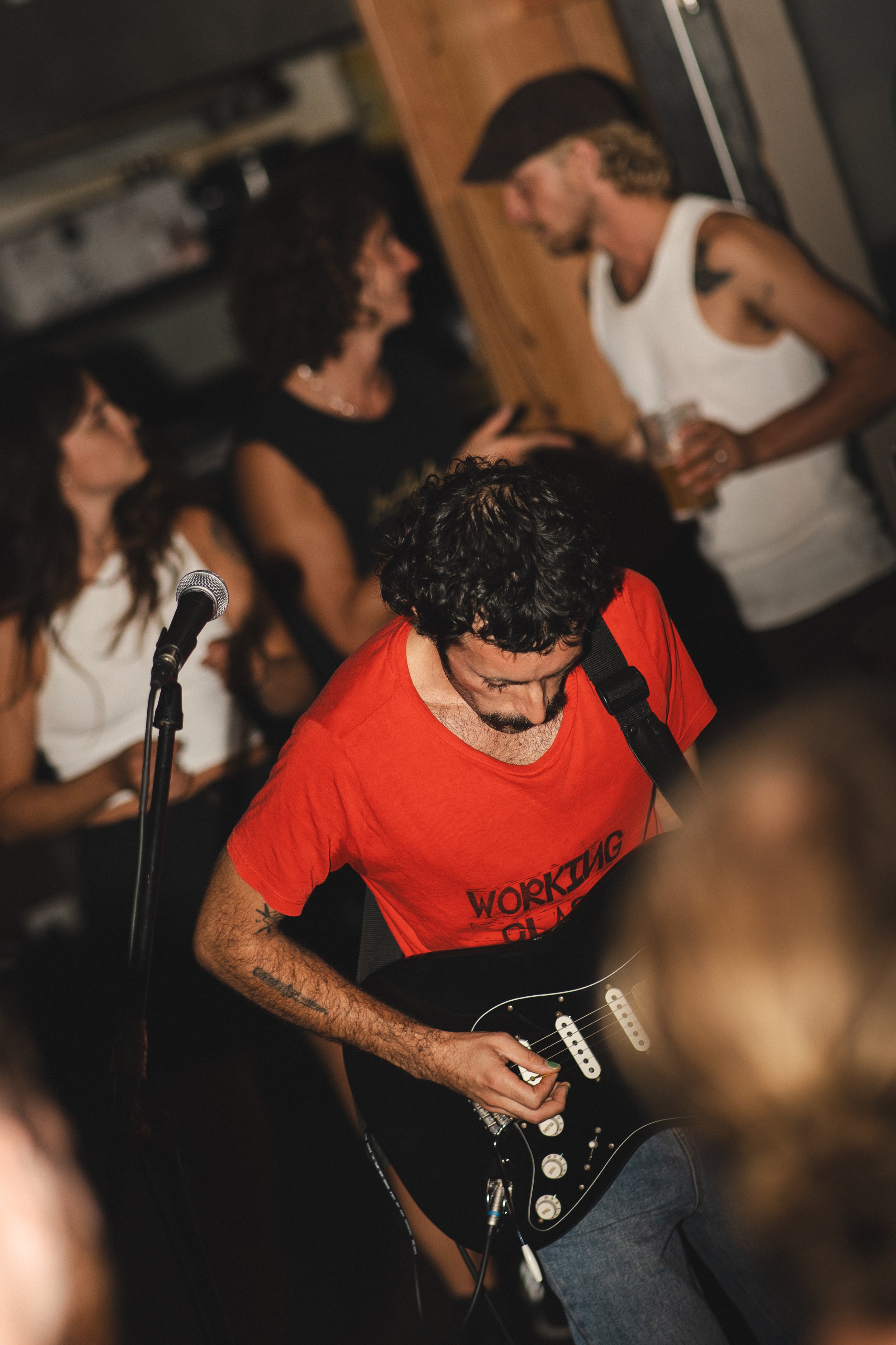 Editorial event photography in Noosa of a guitarist performing at a social gathering with guests enjoying drinks