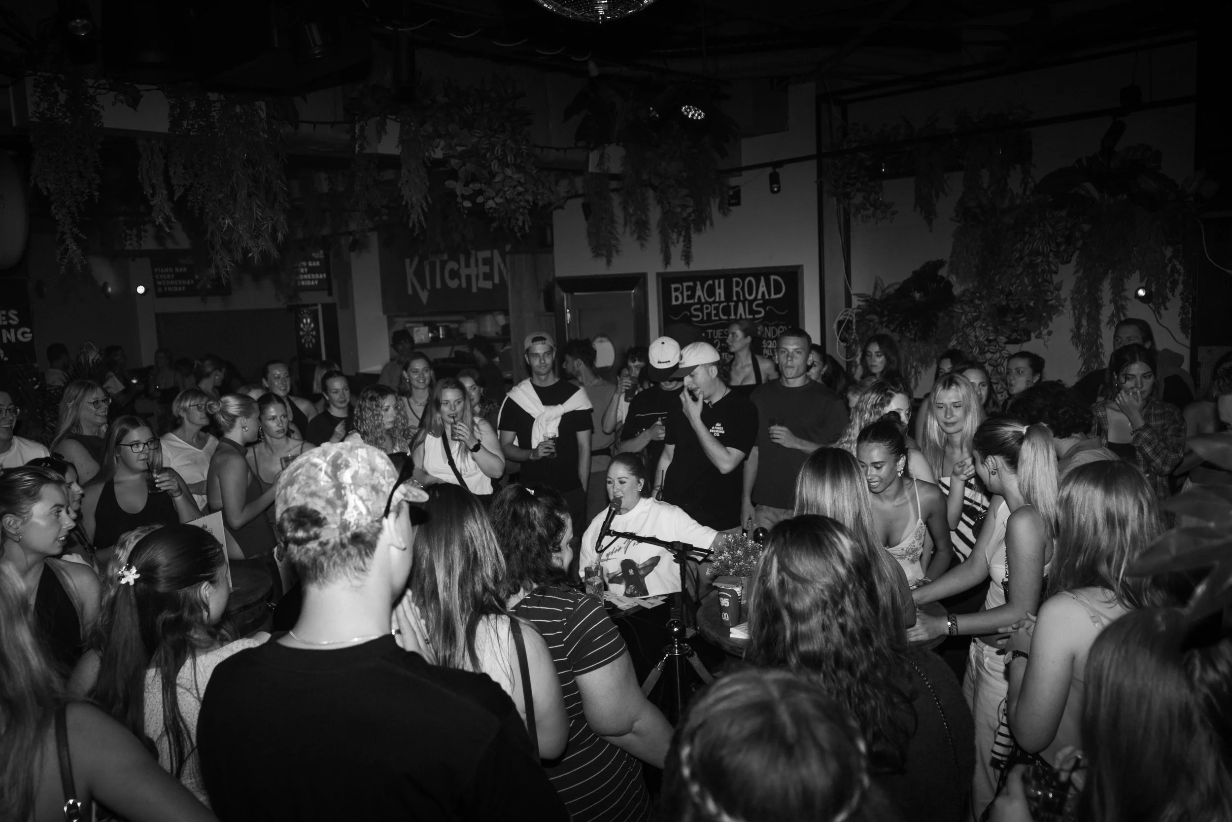Candid black and white capture of guests engaging with live music at a Noosa venue, vibrant crowd and styled decor, ideal for Sunshine Coast event and hospitality photography