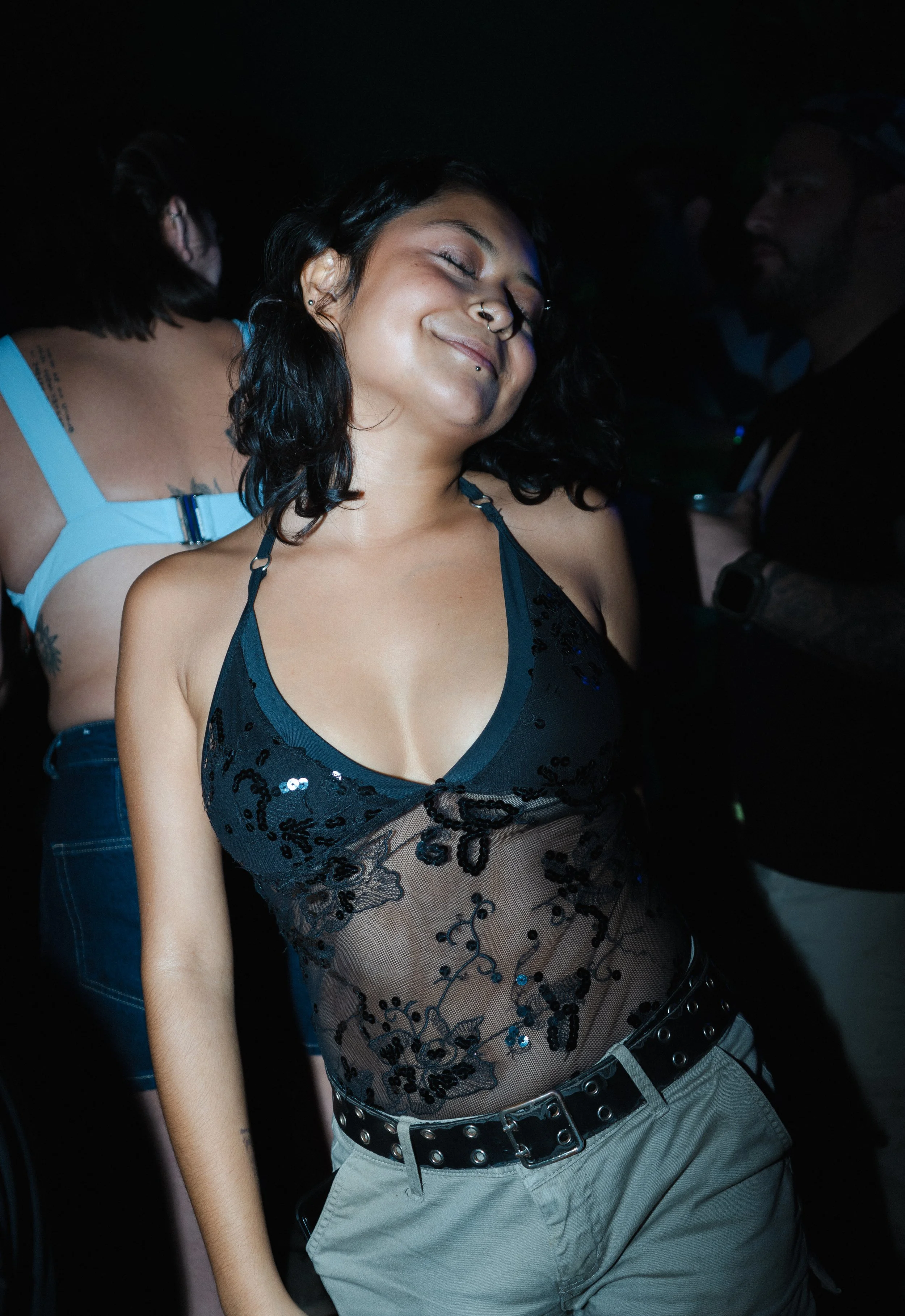 Nightlife candid shot of a guest dancing and enjoying the atmosphere, stylish outfit and low light setting.