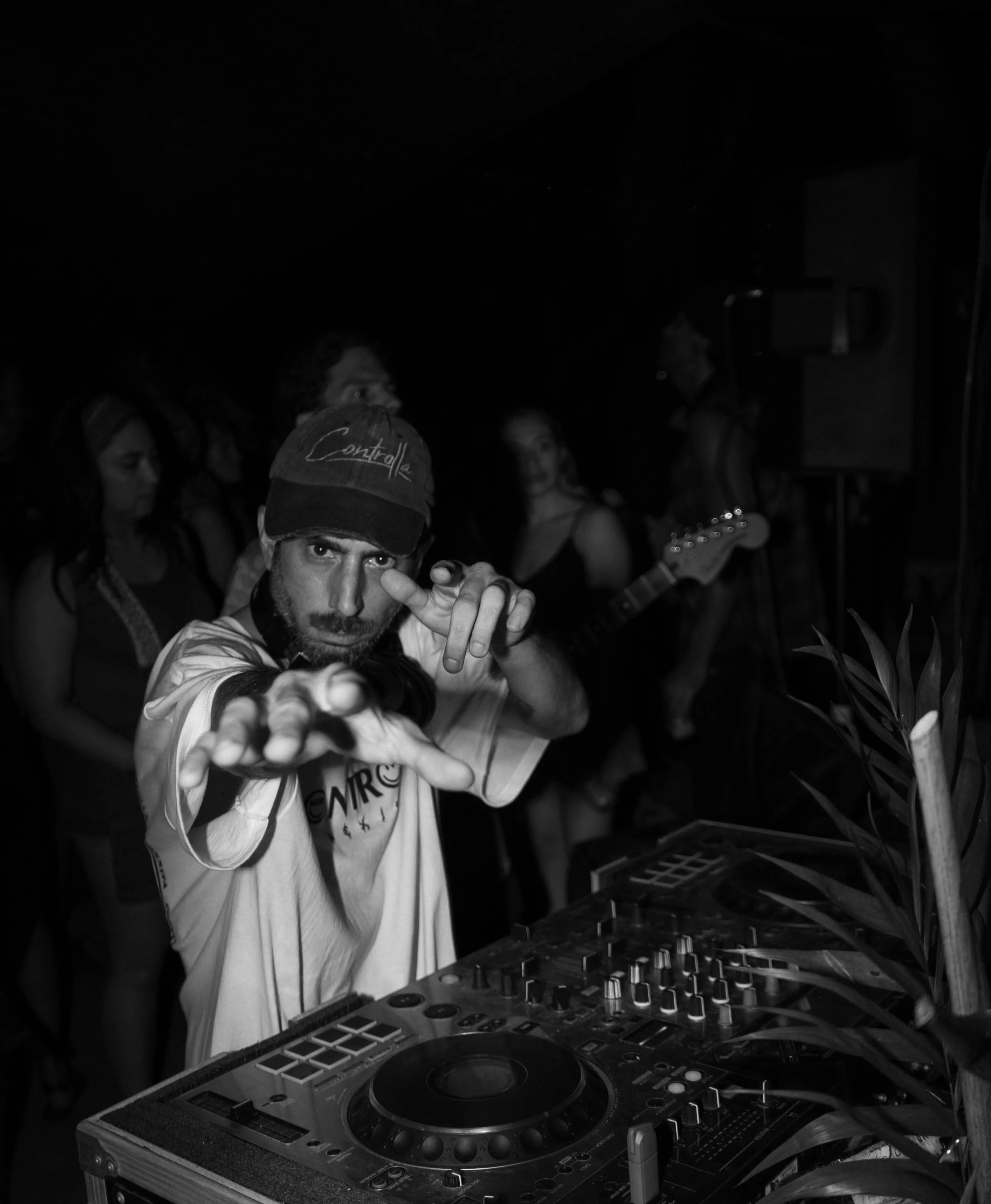DJ with beard and cap pointing at the camera while performing at a party in Noosa, crowd and live music in background, Sunshine Coast event and nightlife photography