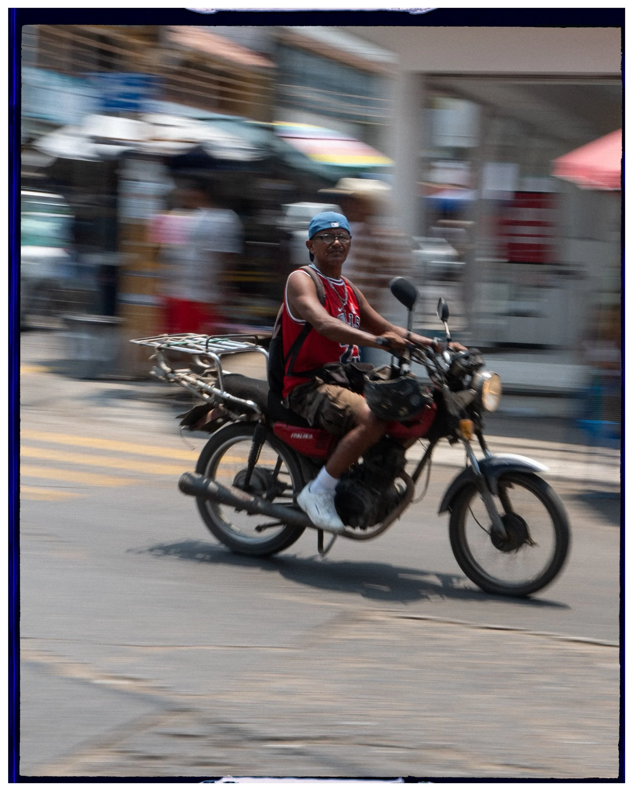 travel and street photography of a man riding a motorbike on a busy city street