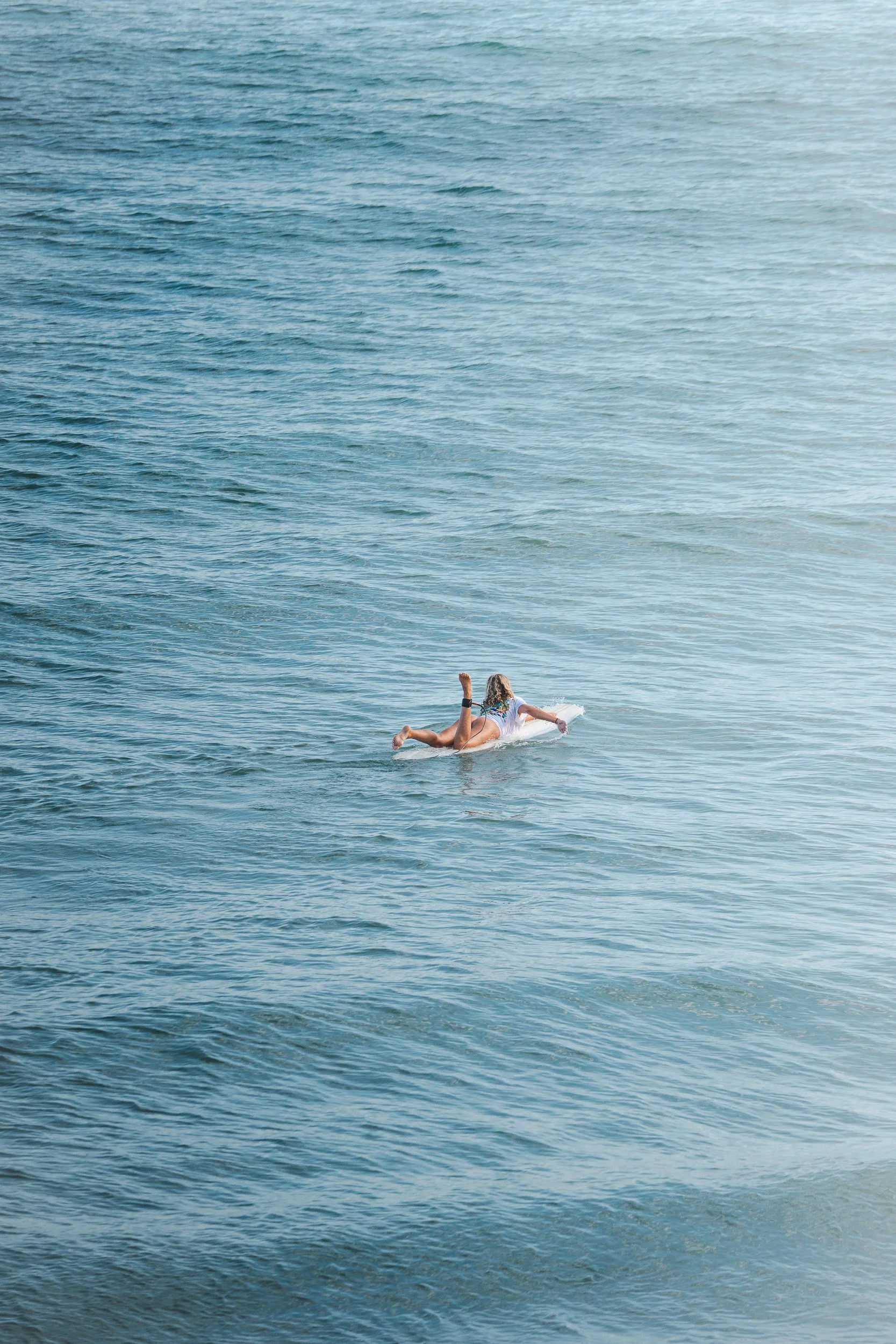 Person surfing the ocean on a surfboard at the beach.