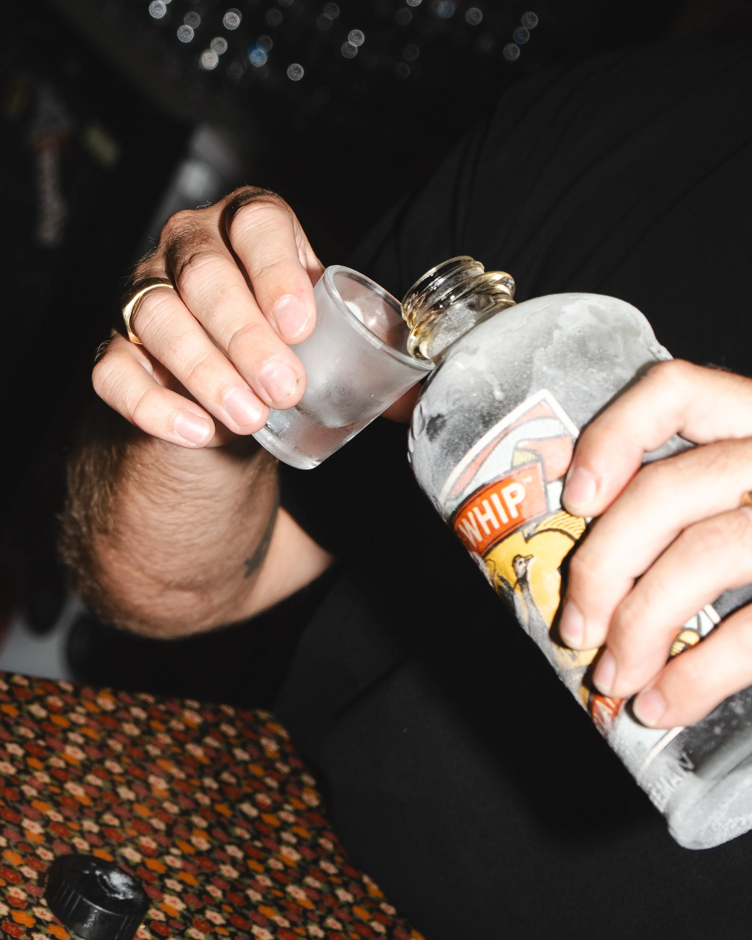 Person pouring a shot of vodka from a Frosty Jack's container into a glass.