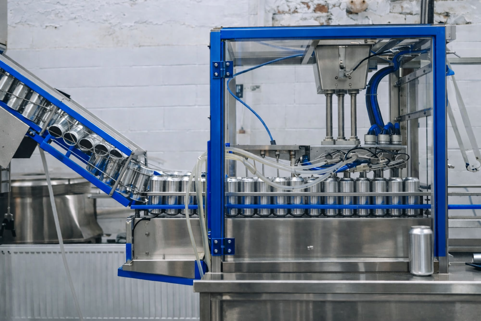Industrial can filling machine with metal cans on conveyor belt, in a factory setting.