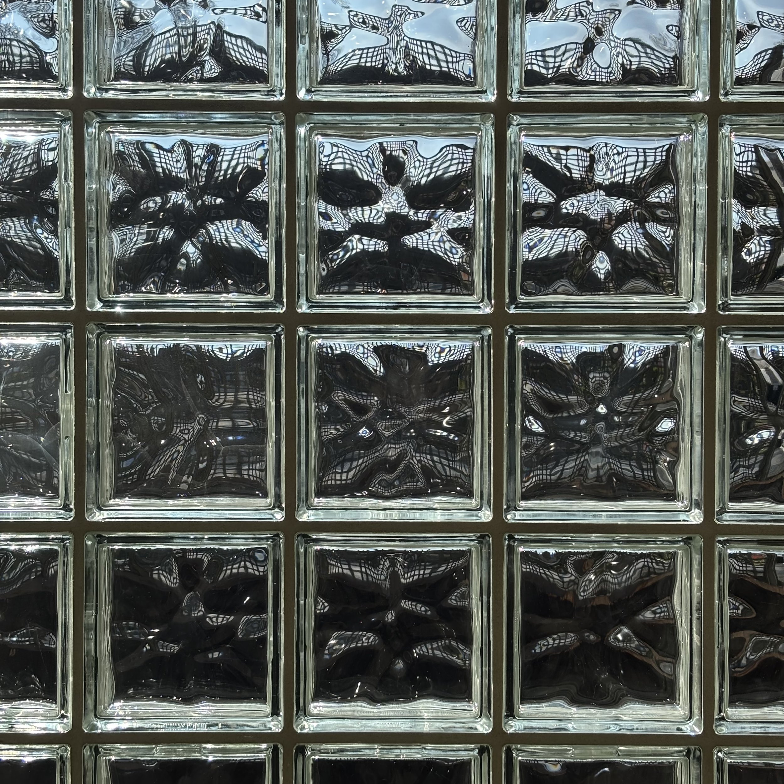 Close-up of glass blocks with black and white abstract reflections and patterns.