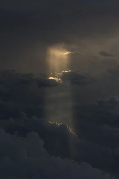 A beam of sunlight breaking through dark storm clouds in the sky.