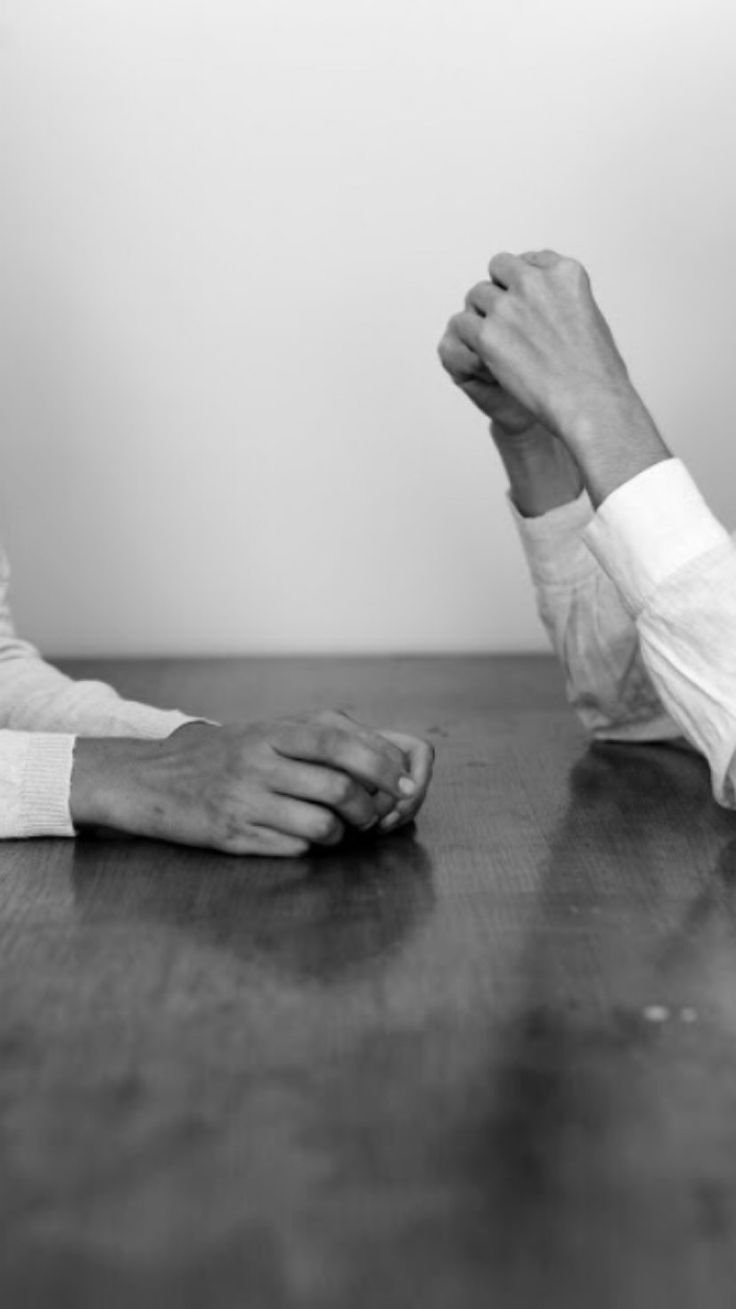 Two peoples hands sit opposite each other in black and white