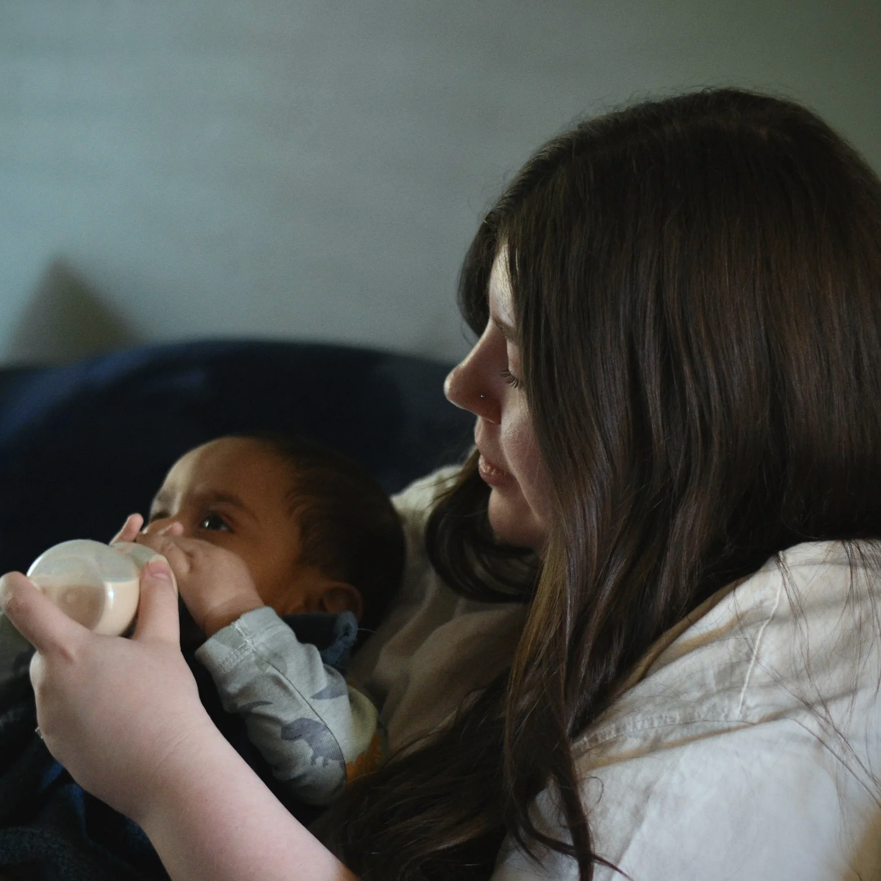 Woman feeding a young child with a bottle.