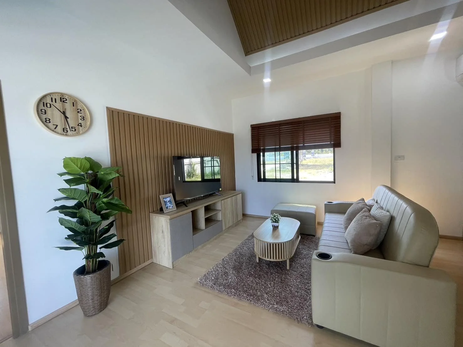 A cozy and inviting lounge area with a textured feature wall, wooden media console, and a large window providing views of the lush tropical surroundings.
