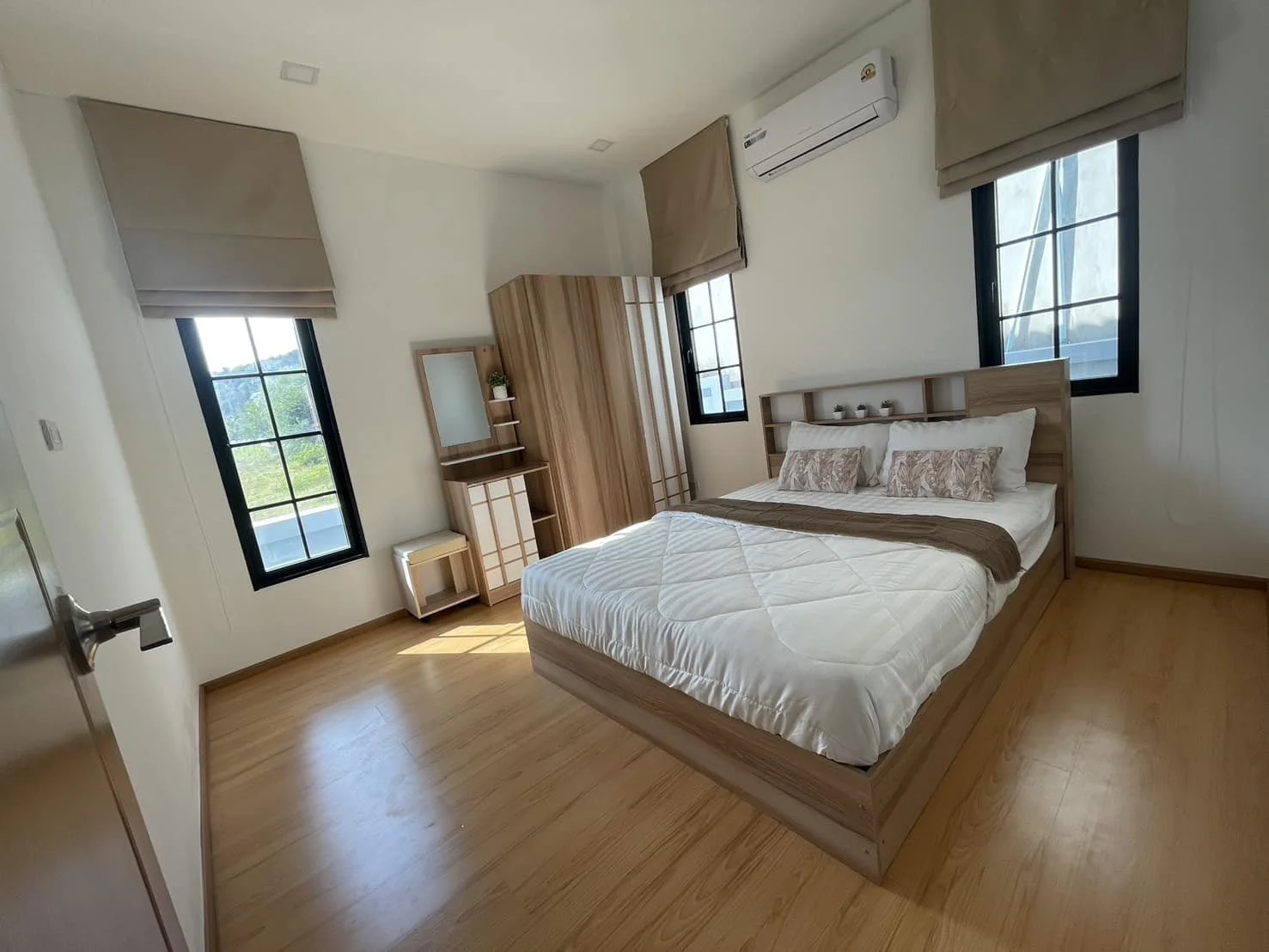 A masterfully designed bedroom suite featuring warm wood floors, modern air conditioning, and a minimalist vanity.
