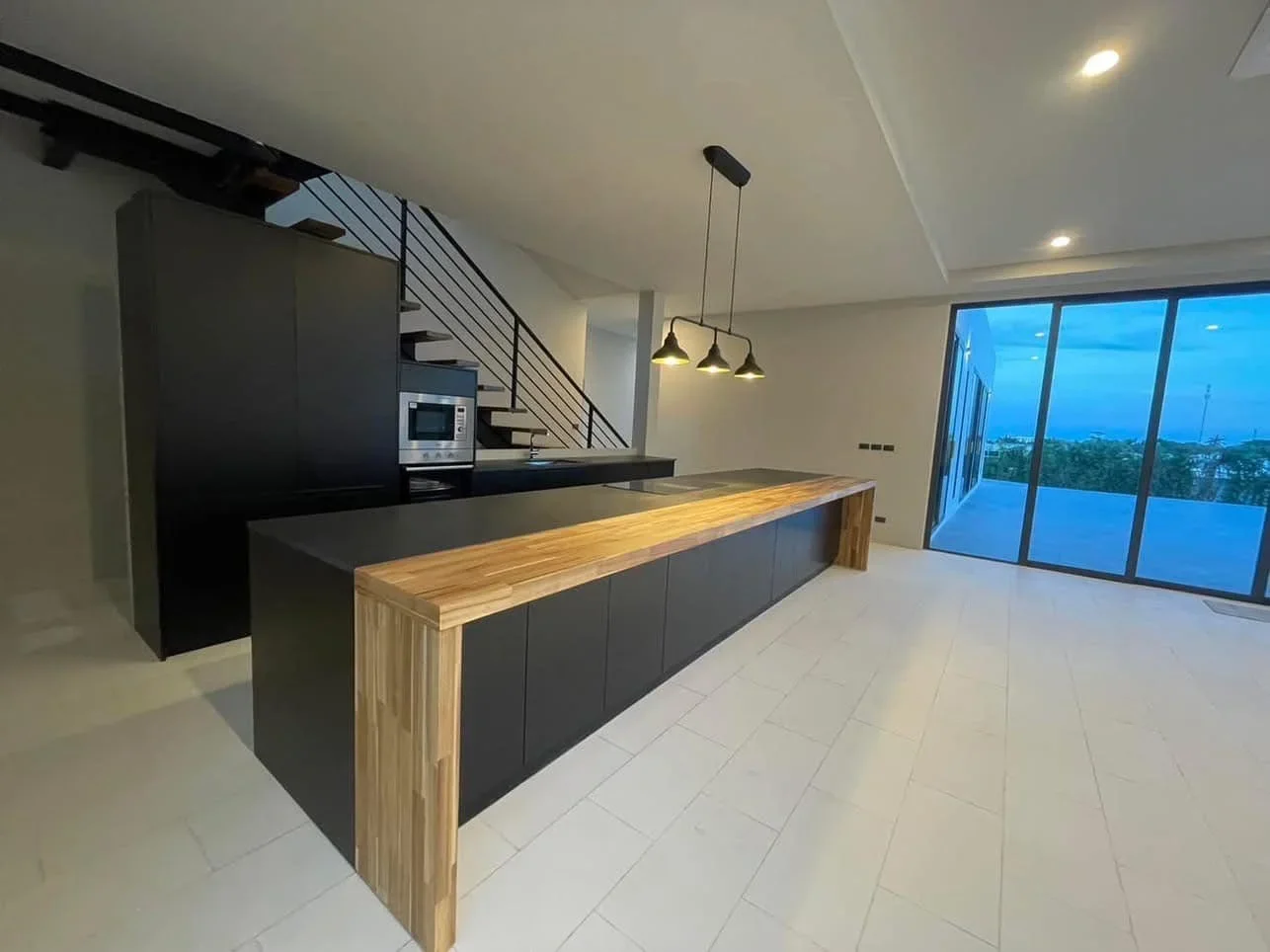 Fully equipped modern kitchen with integrated appliances, island, and dining area in a brand-new resale villa.
