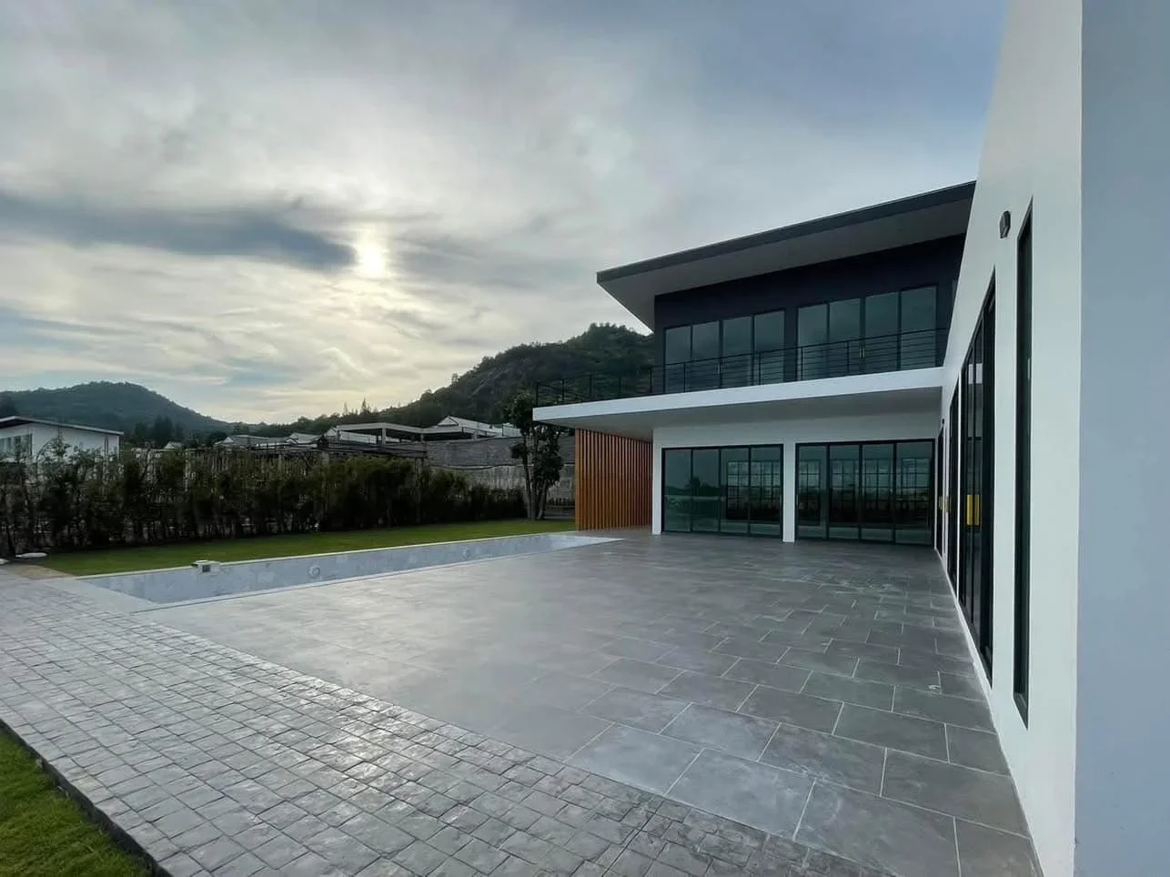 Wide-angle perspective of the pool terrace and landscaped garden under a mountain backdrop, highlighting the privacy of the property.
