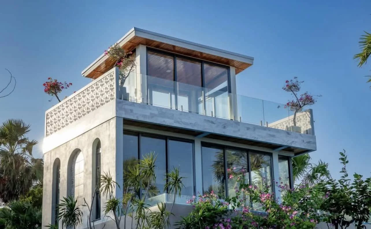 Architectural Profile: A low-angle view highlighting the villa's multi-level glass balconies and sleek white stucco finish.