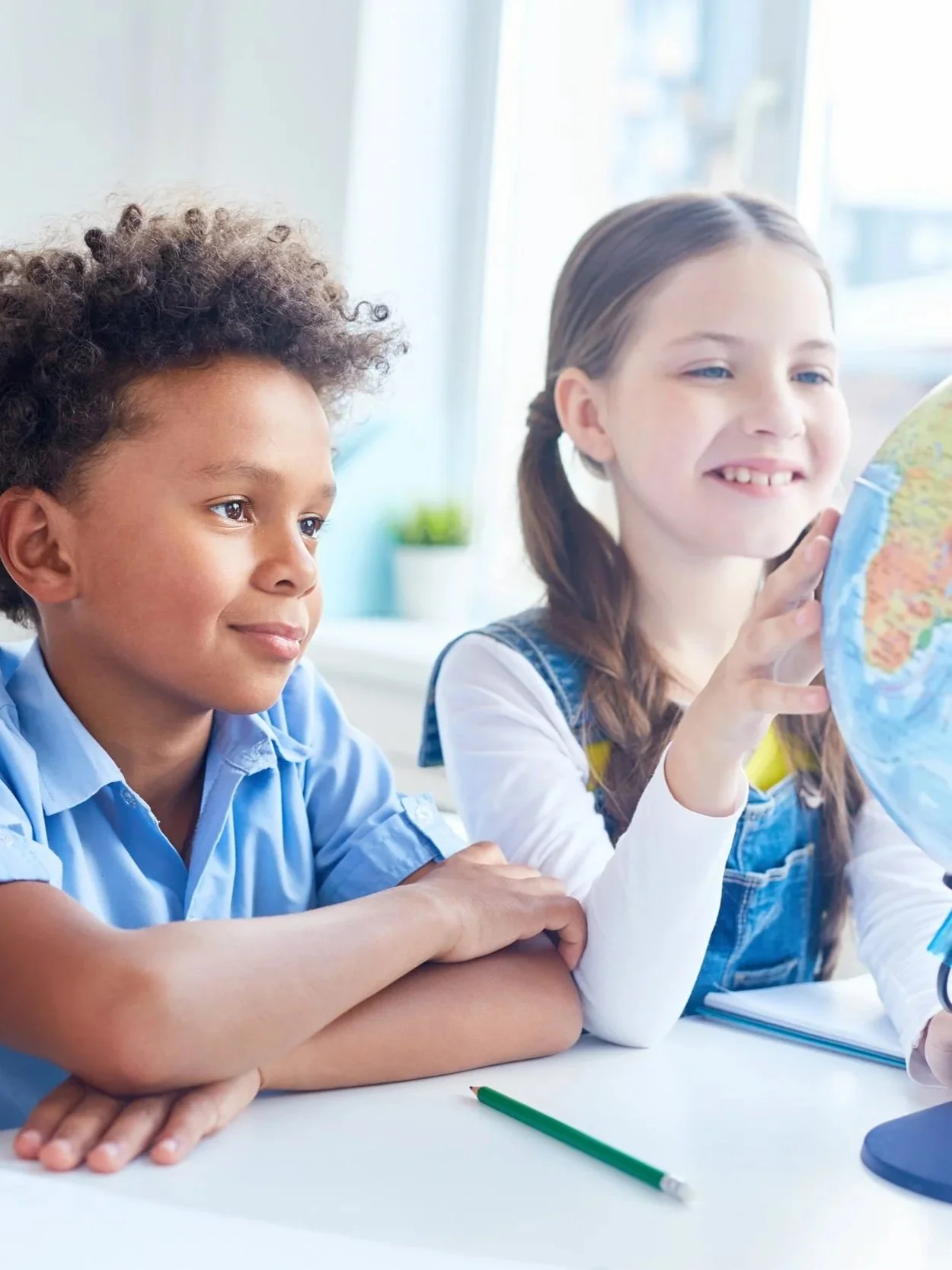 Multicultural students collaborating with a globe in a classroom, representing international standard curricula and global educational excellence available near BeHome Plus curated properties in Hua Hin.