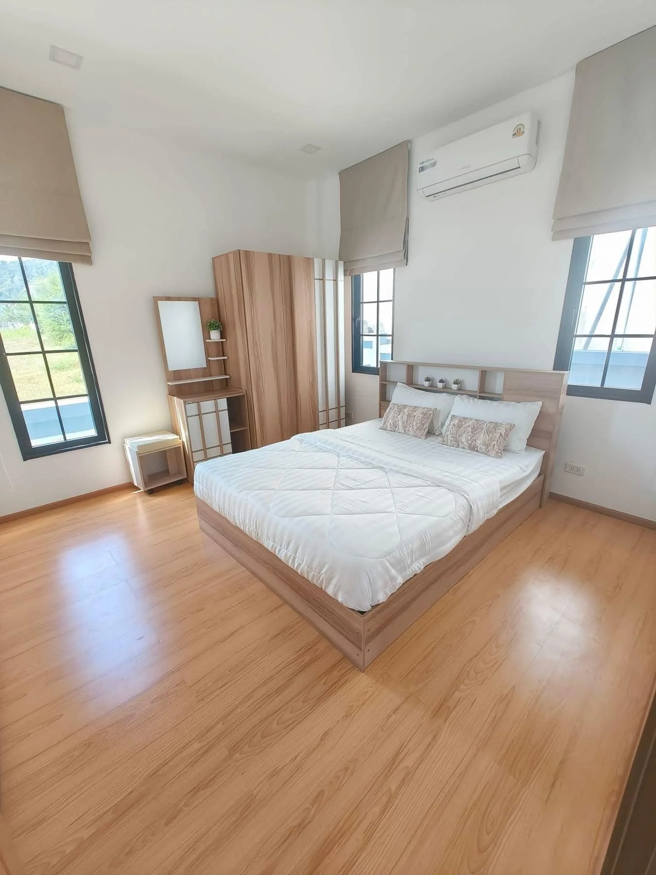 A beautifully appointed guest bedroom featuring built-in wardrobes, a modern vanity desk, and large windows.