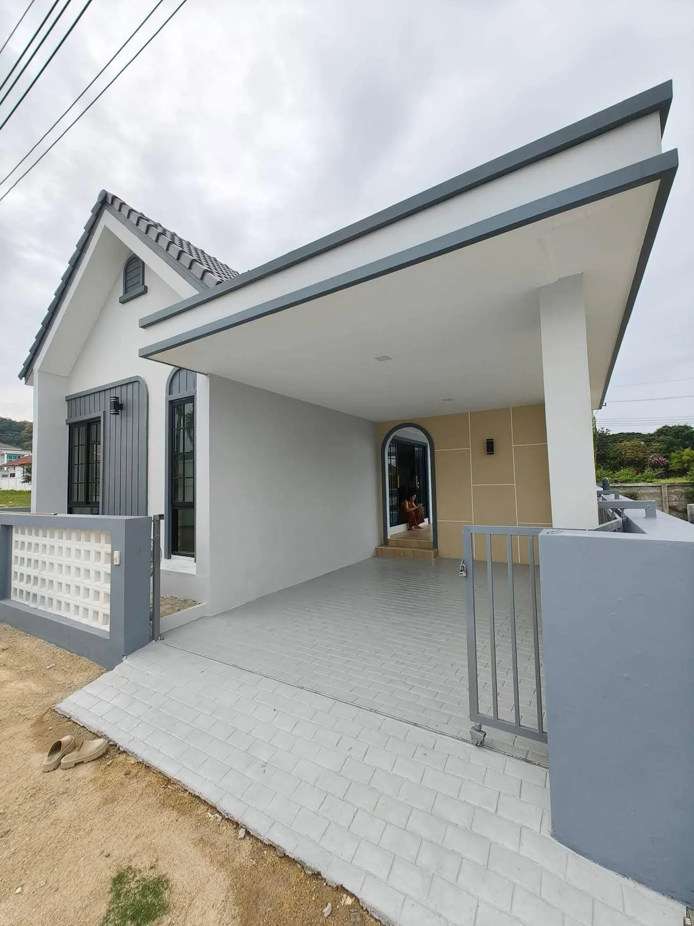 An exterior perspective of the modern villa's entrance, highlighting the clean architectural lines, integrated private carport with grey paving.