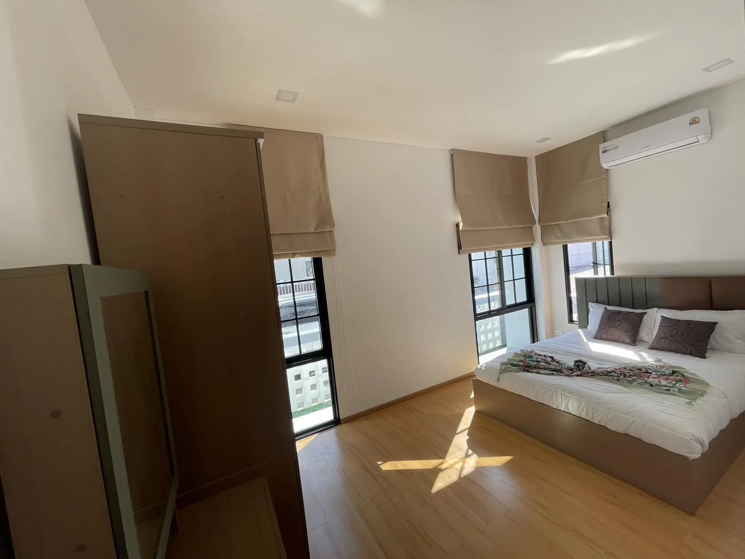 A sun-drenched master bedroom showcasing a king-sized bed, sleek built-in furniture, and large windows that offer a bright and airy atmosphere for relaxation.