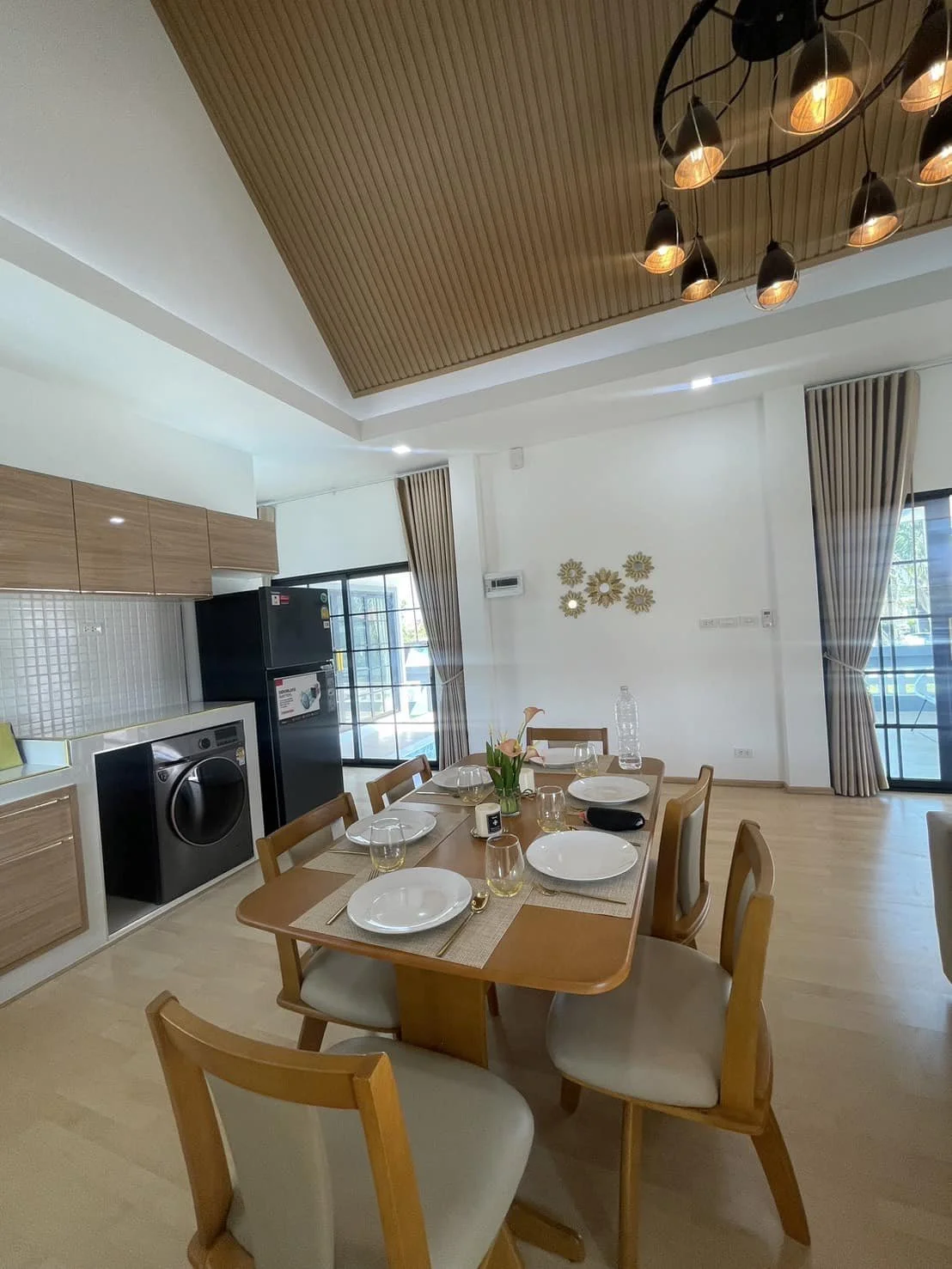 A focused view of the dining area and contemporary kitchen, highlighting the functional layout and the elegant minimalist chandelier.
