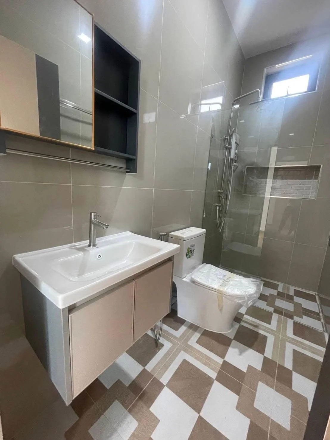 A contemporary bathroom featuring textured designer floor tiles, a glass-enclosed walk-in shower with a rainfall head.