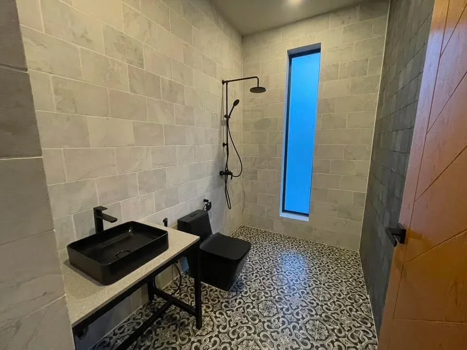 Contemporary bathroom design featuring patterned floor tiles, a black vessel sink, and an industrial-style walk-in rain shower.