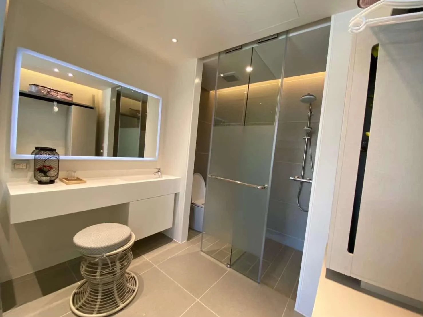 Minimalist Wellness Suite: A bright and airy bathroom featuring a sleek white floating vanity and a large backlit mirror.
