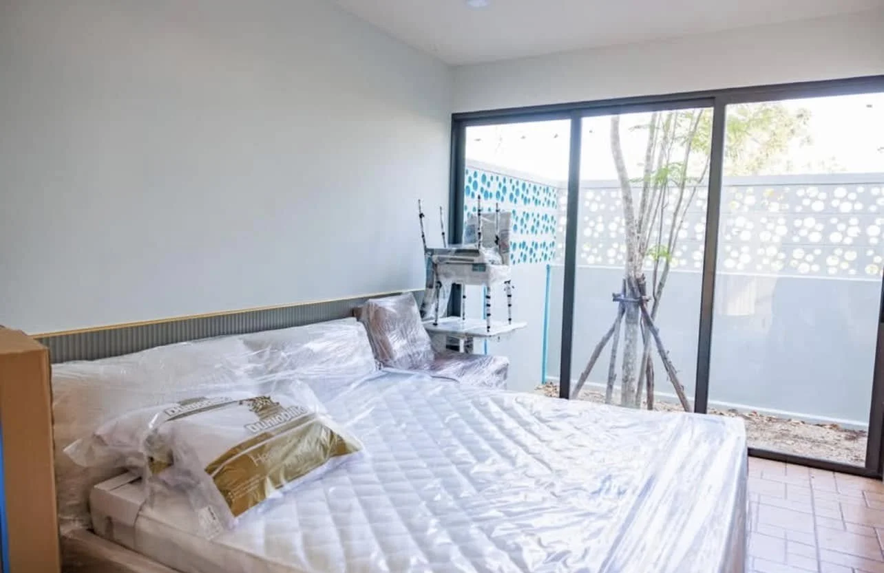 Ground-Level Sanctuary: One of the four expansive bedrooms, currently showcasing its brand-new status with protected furnishings.