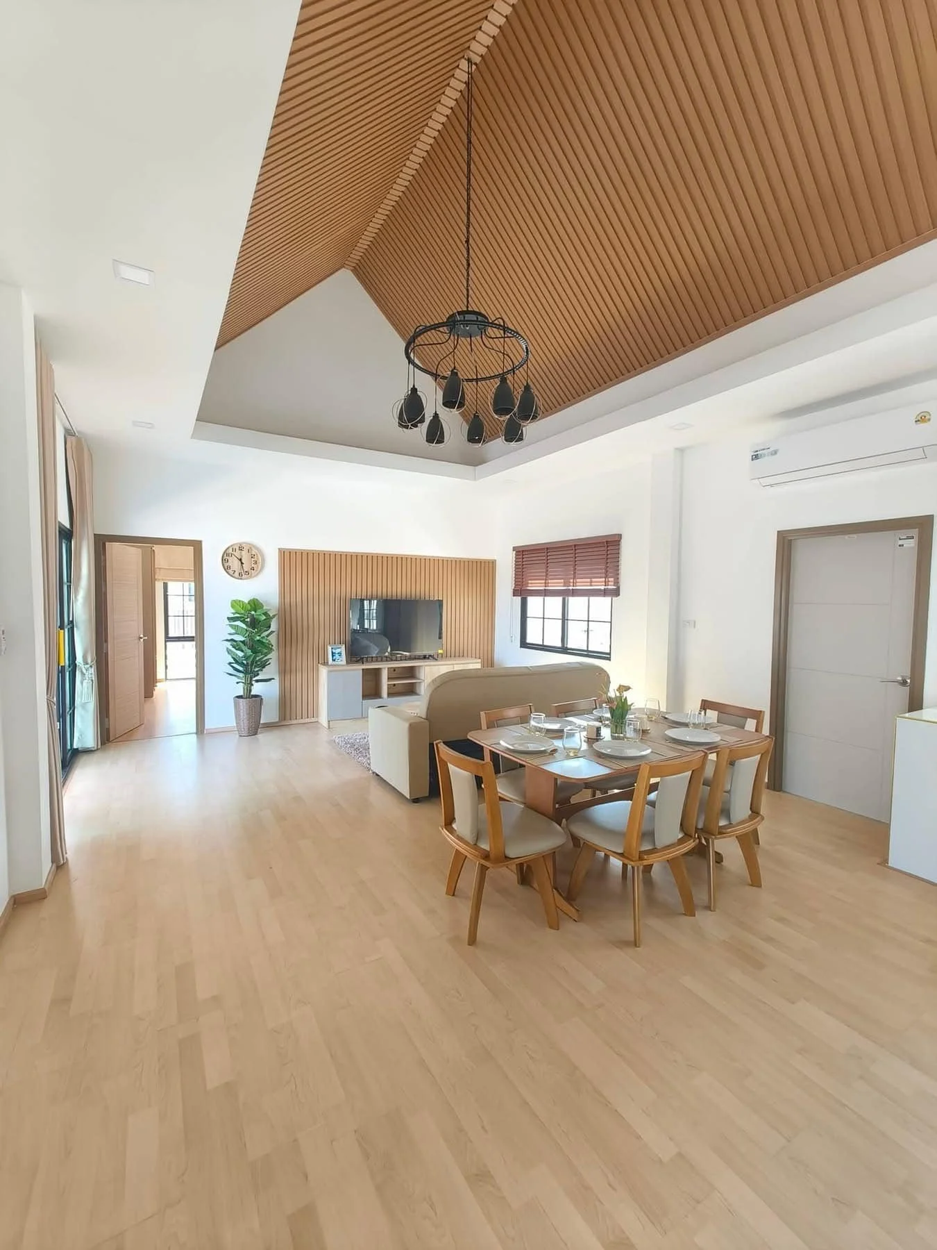 An expansive open-plan living and dining area featuring soaring vaulted ceilings with warm wood paneling.