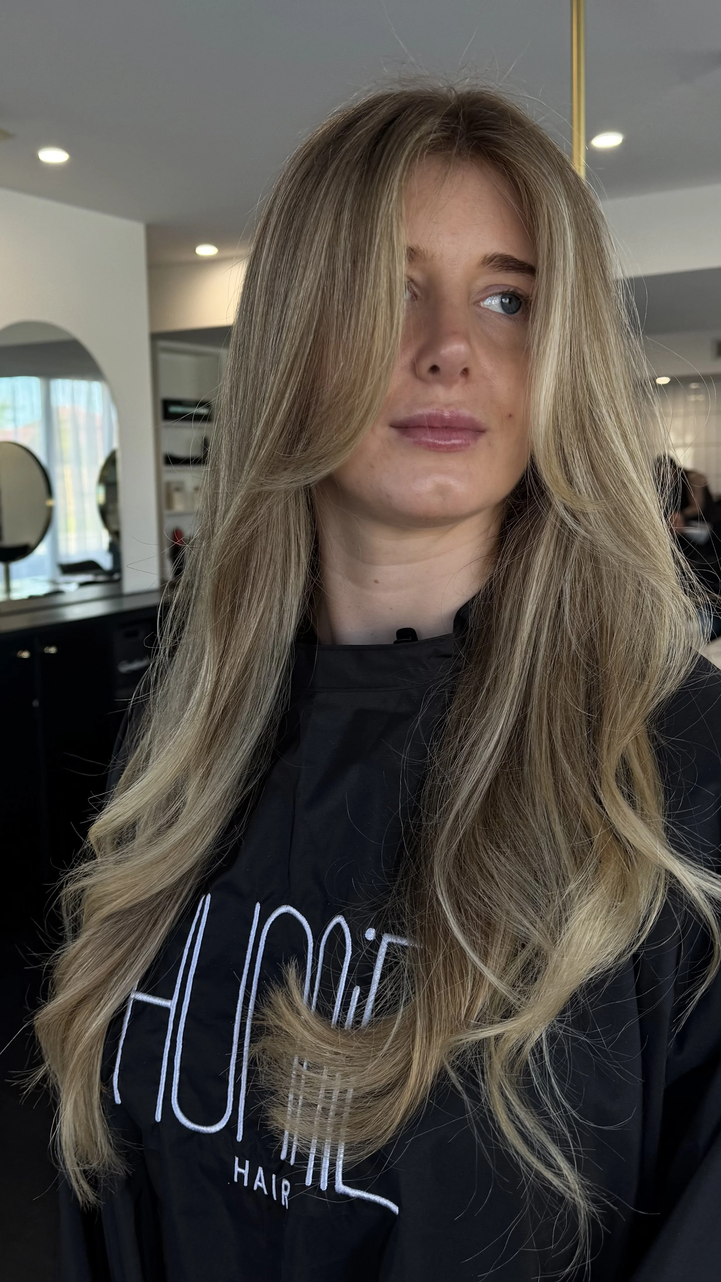 A woman with long blonde hair and blue eyes in a hair salon.