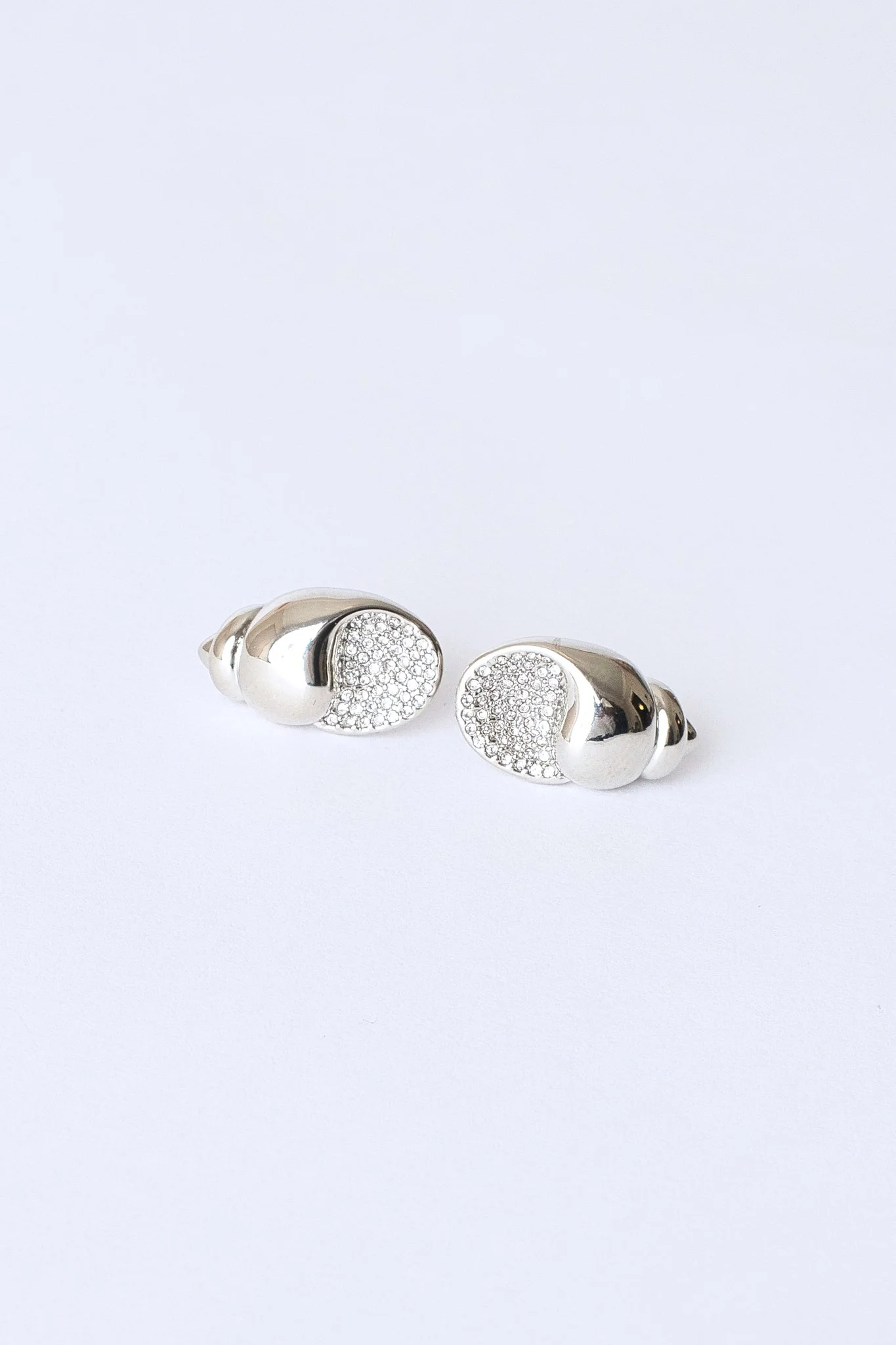 A pair of silver earrings with a curved design, embellished with small sparkling stones, displayed against a plain white background.