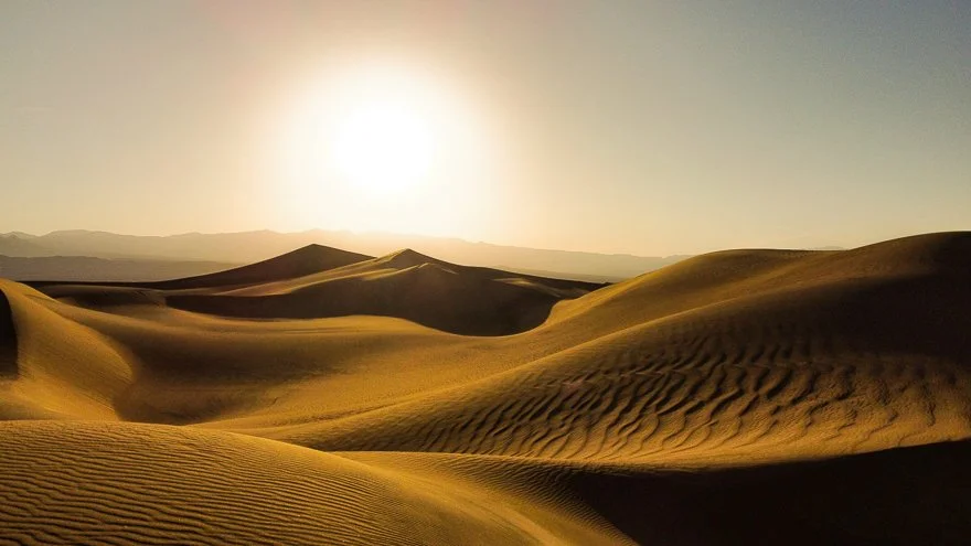 Desert with sand dunes under a clear sky and bright sun
